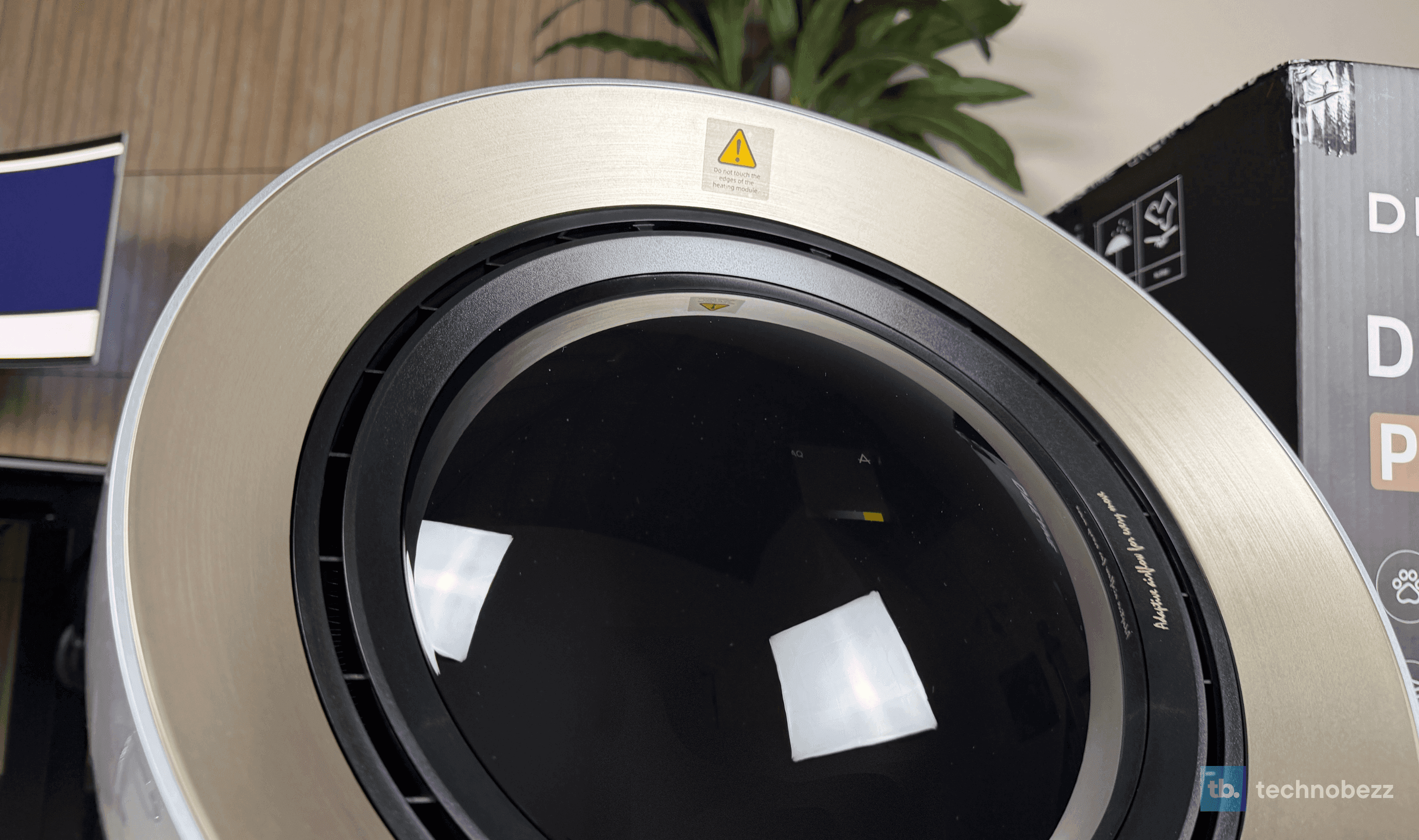 Close-up of the Dreame AirPursue PM20's brushed champagne ring and glass dome, with the heating module warning label