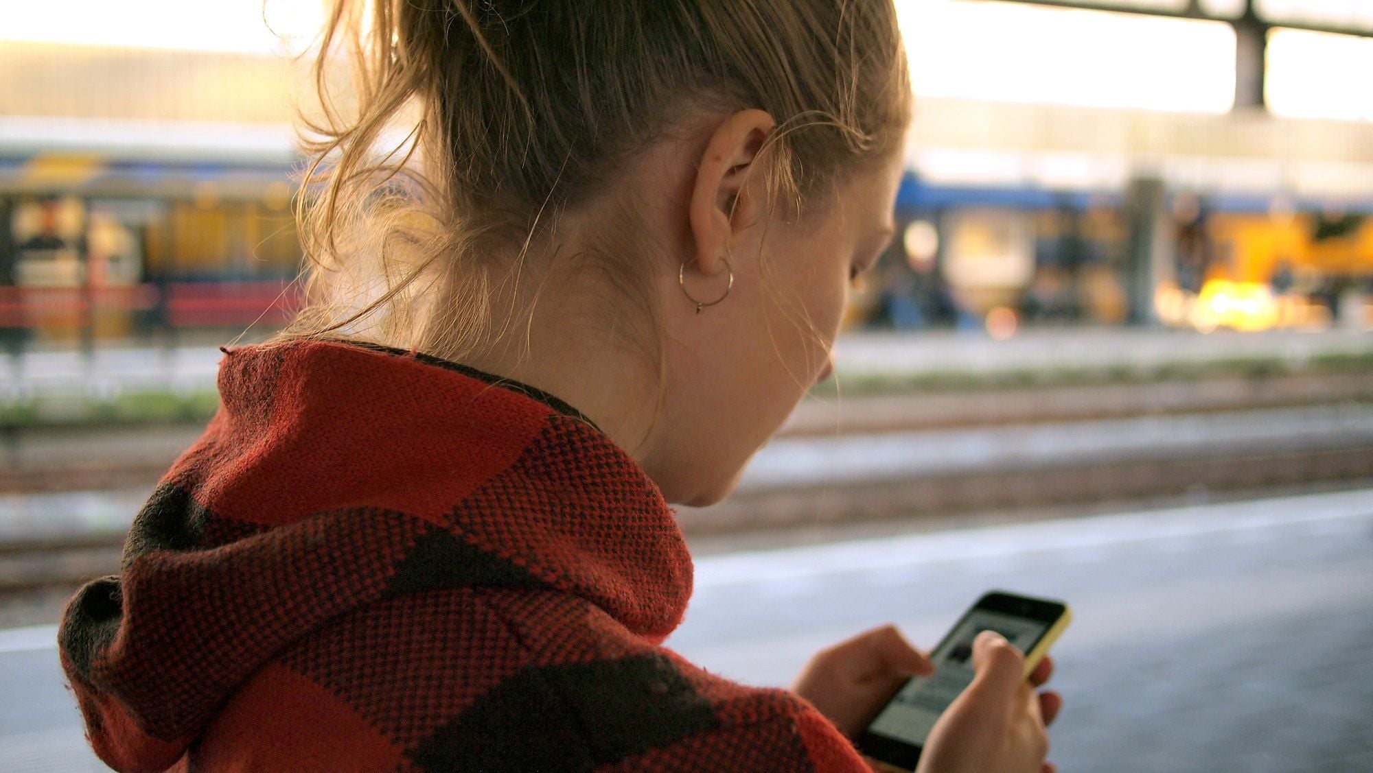 A woman checking her phone on a train platform