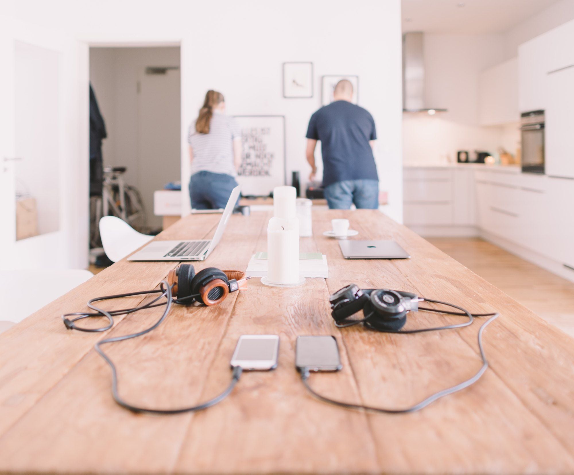 Two people at home with their phones and laptops on a table
