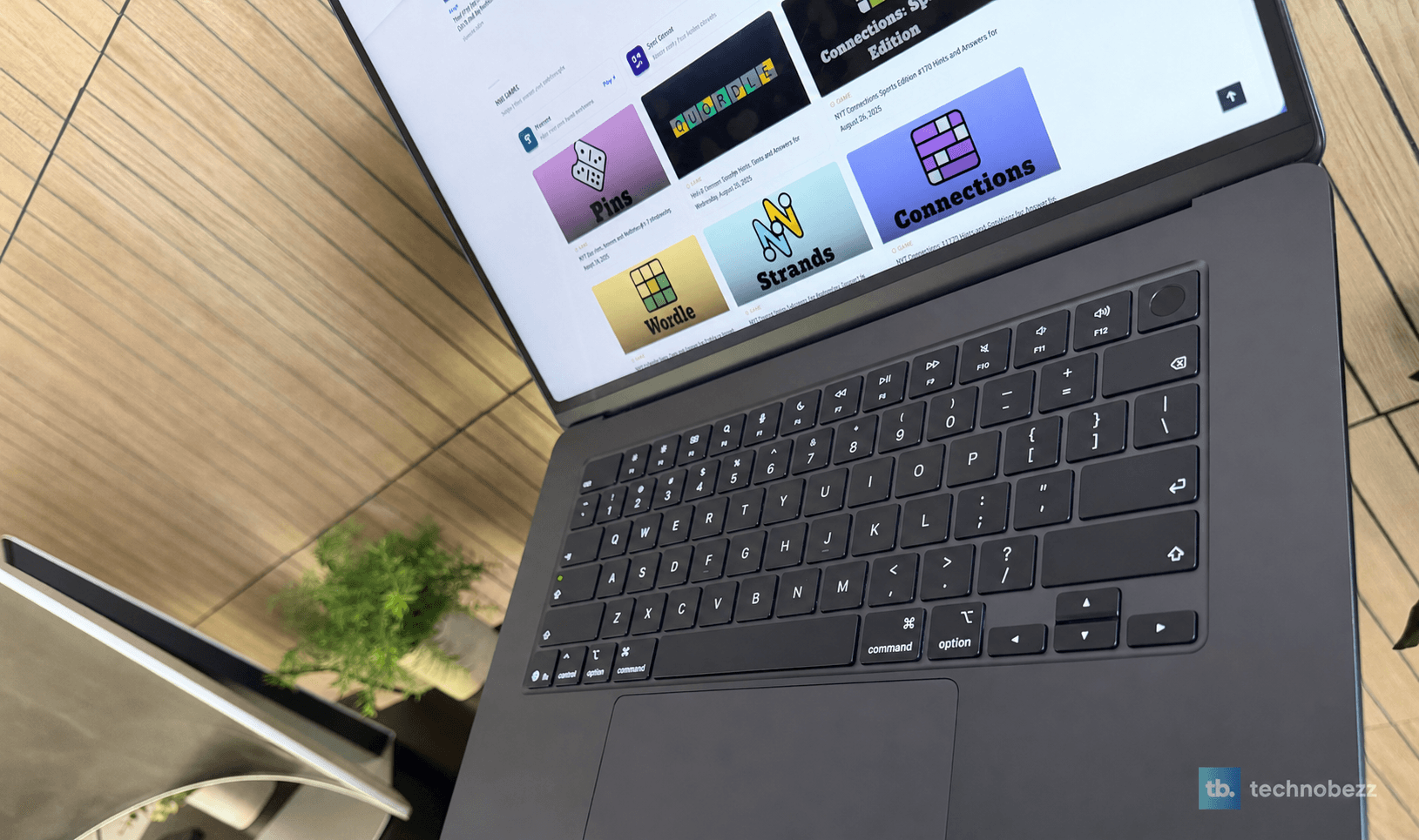 MacBook Air M5 keyboard and display showing Technobezz game pages