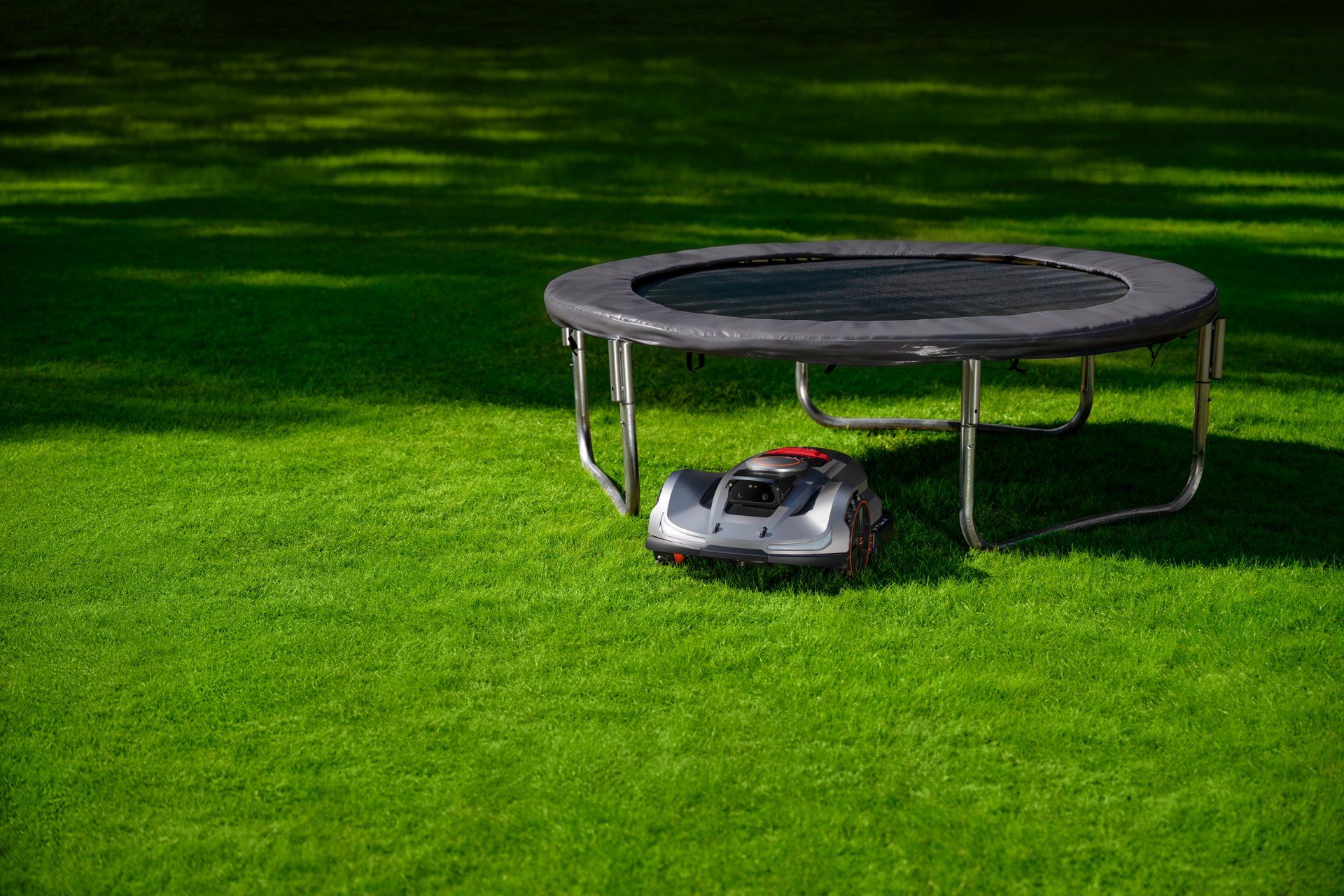 Sunseeker Elite X7 Gen 2 robot mower mowing under a backyard trampoline