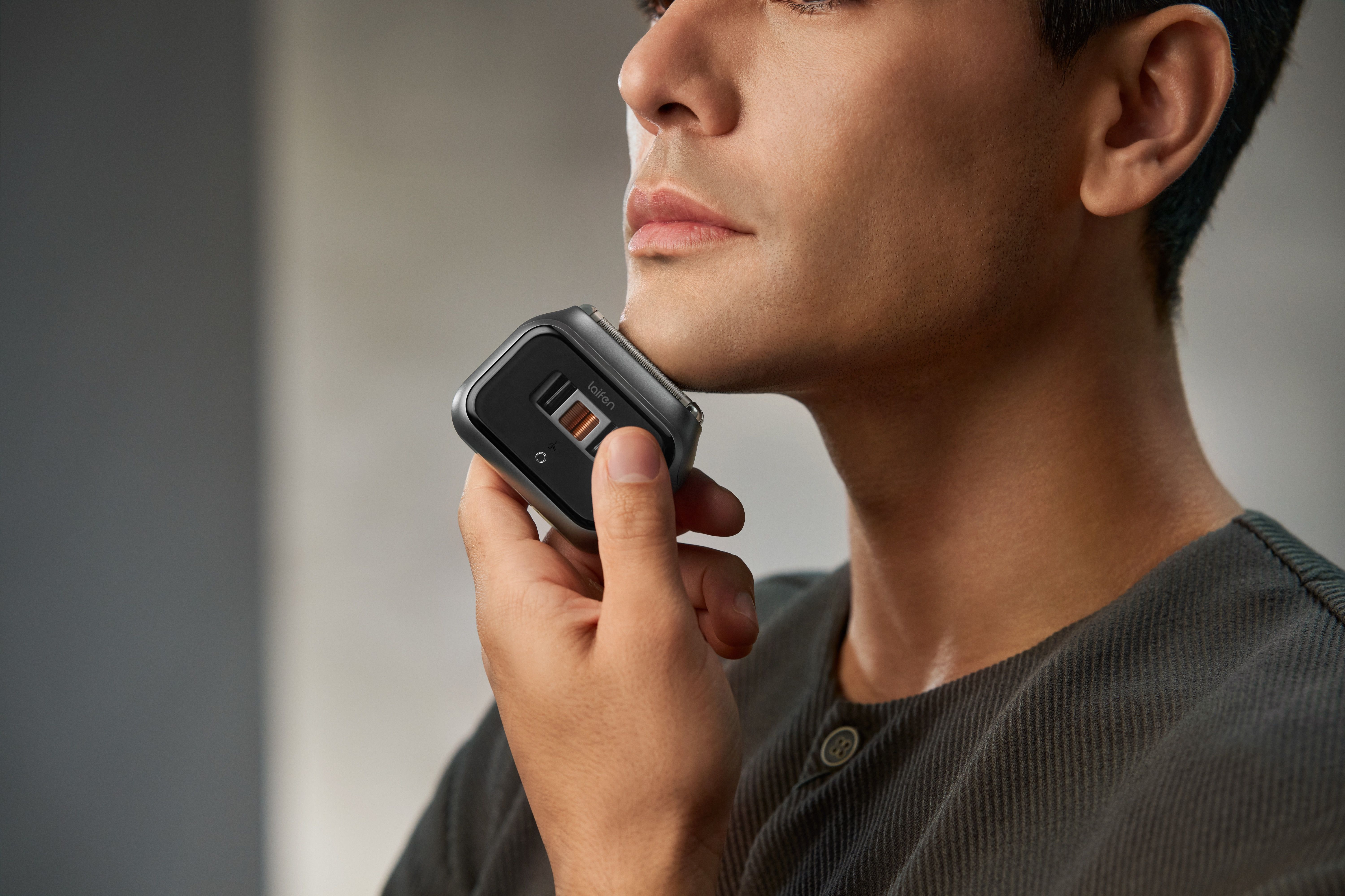 A man shaving along his jawline with the dark gray Laifen P3 Pro electric shaver