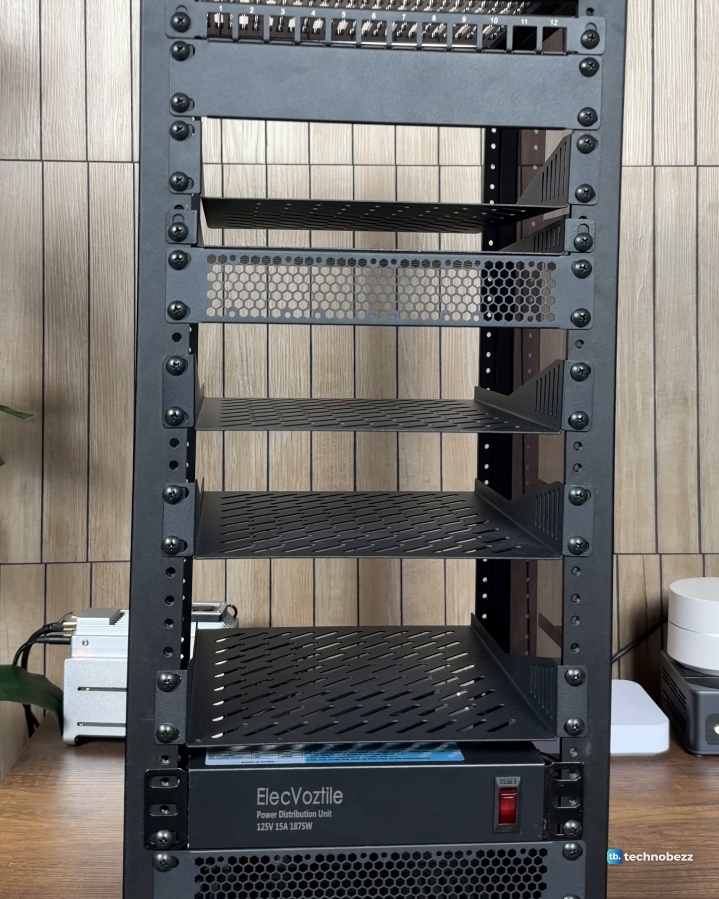 The empty 12U 10-inch rack from the front with a patch panel at the top, vented shelves in the middle and a power strip at the bottom