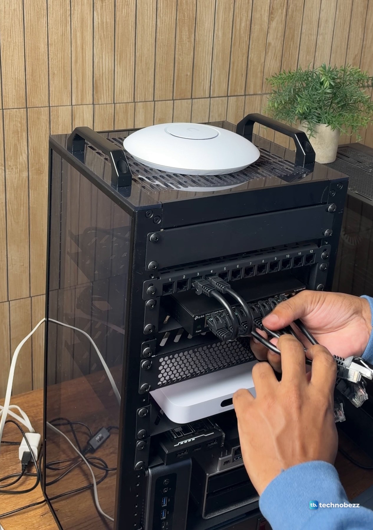 Hands plugging short black patch cables from the patch panel into the 8-port switch inside the DeskPi RackMate T2
