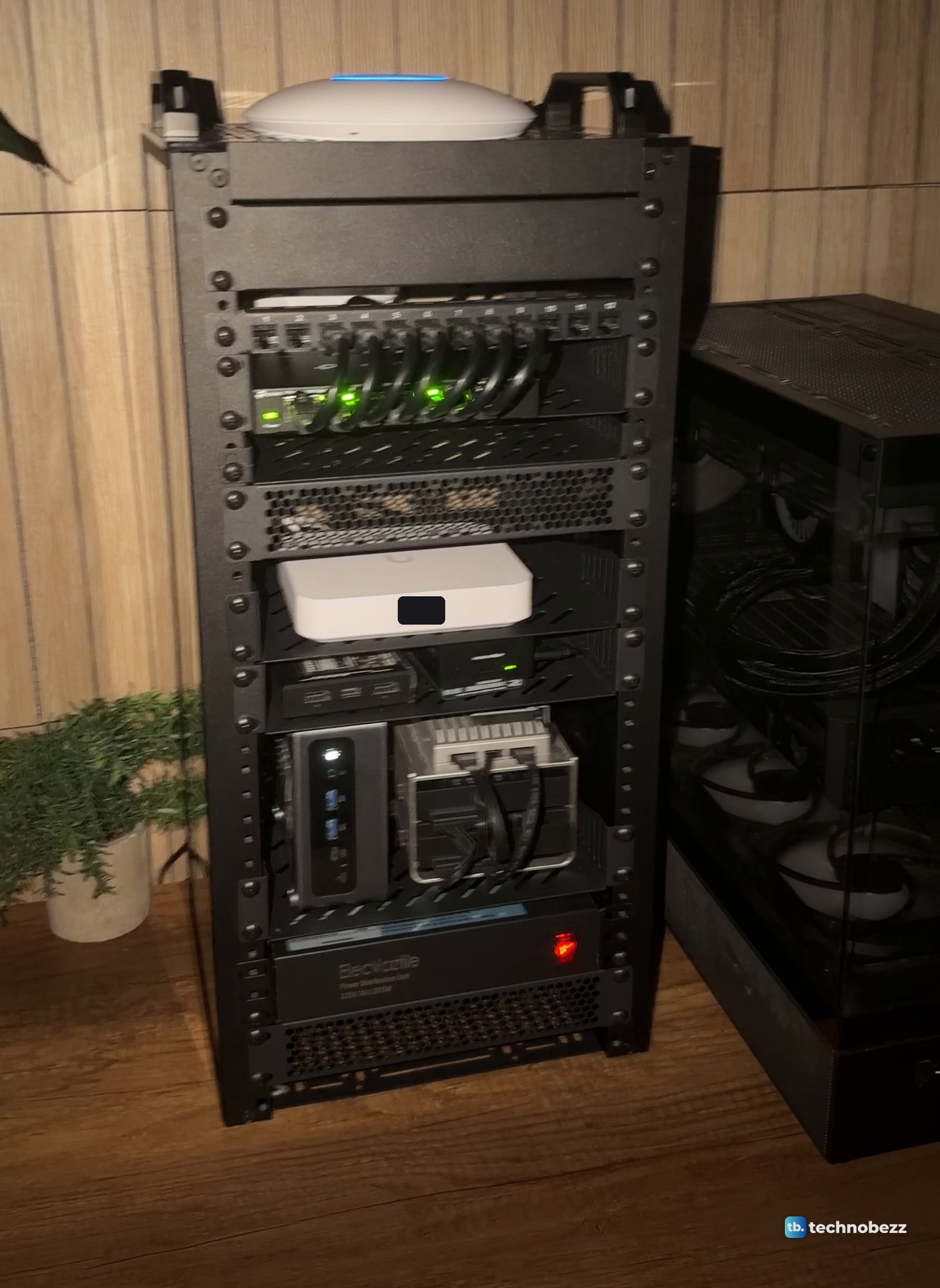 The DeskPi RackMate T2 in dim warm light at night with green switch lights, the gateway light and the access point's blue ring