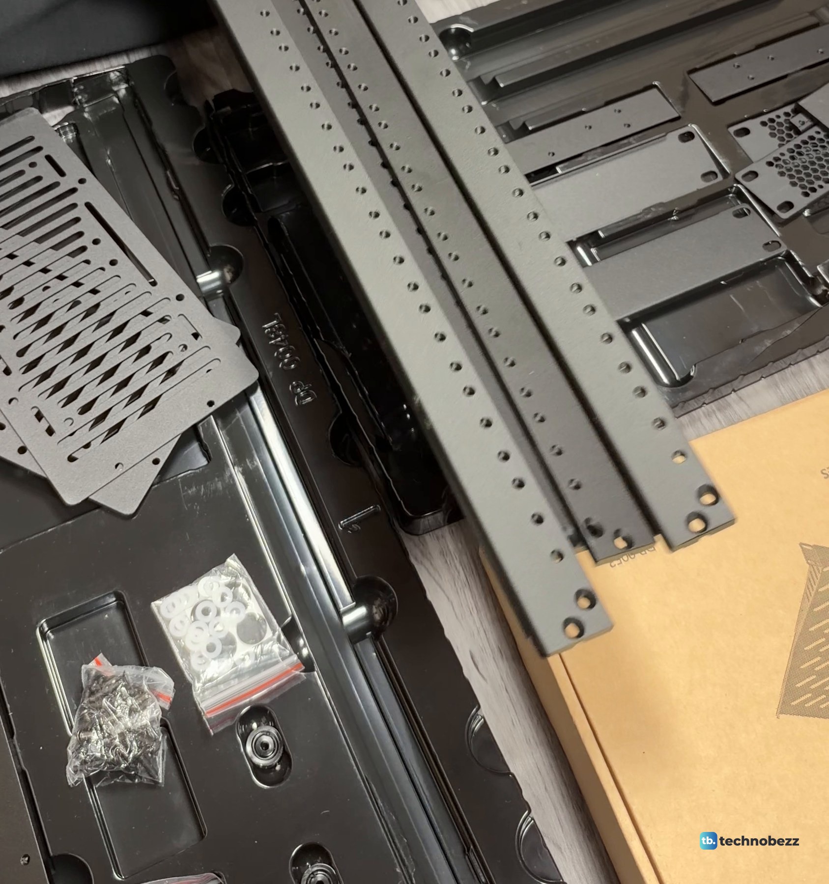 DeskPi RackMate T2 rack rails laid together on the floor beside screw bags and a bag of white washers