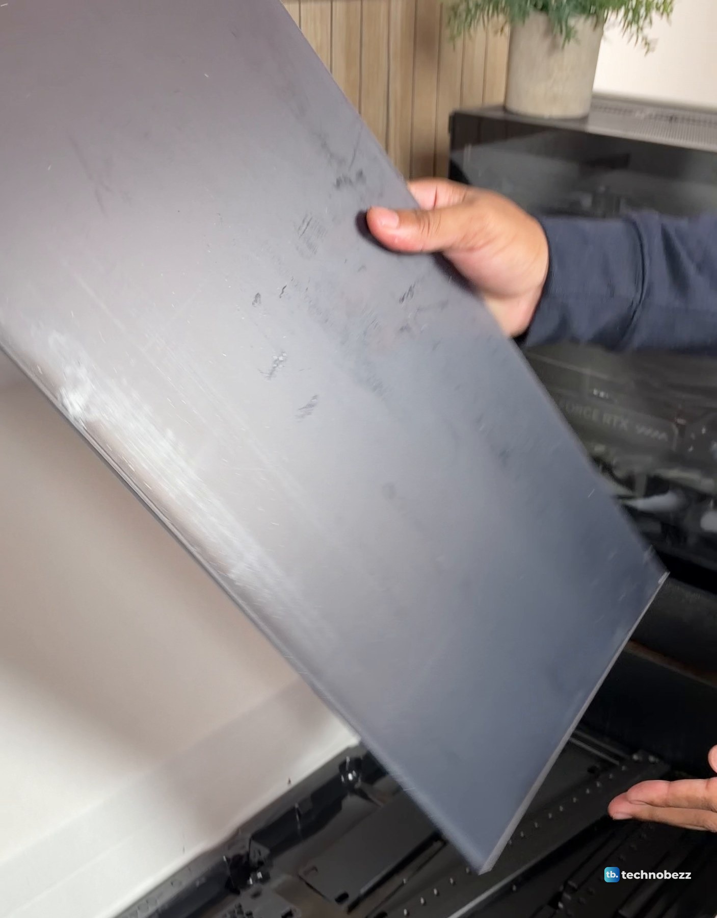 A hand lifting a large smoked acrylic side panel out of the DeskPi RackMate T2 box