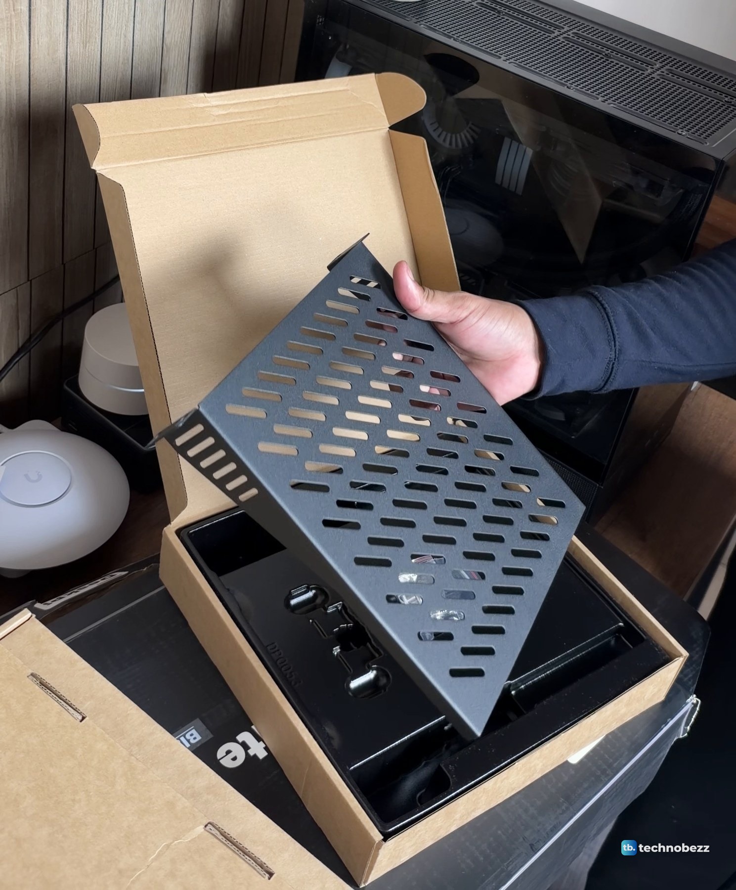 A black vented 1U rack shelf being lifted out of its brown box