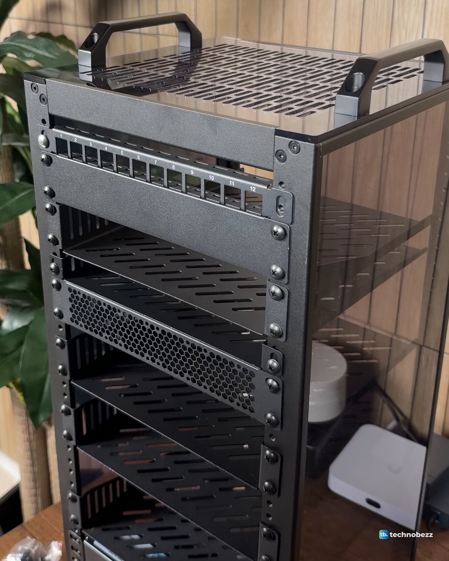 The empty 10-inch rack at an angle with its carry handles, vented top, a 12-port panel near the top and vented shelves down the front