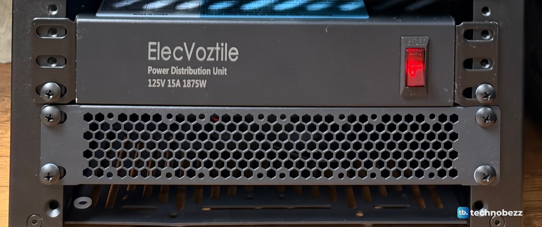 The black ElecVoztile 10-inch PDU with a red switch, above a vented panel at the bottom of the rack
