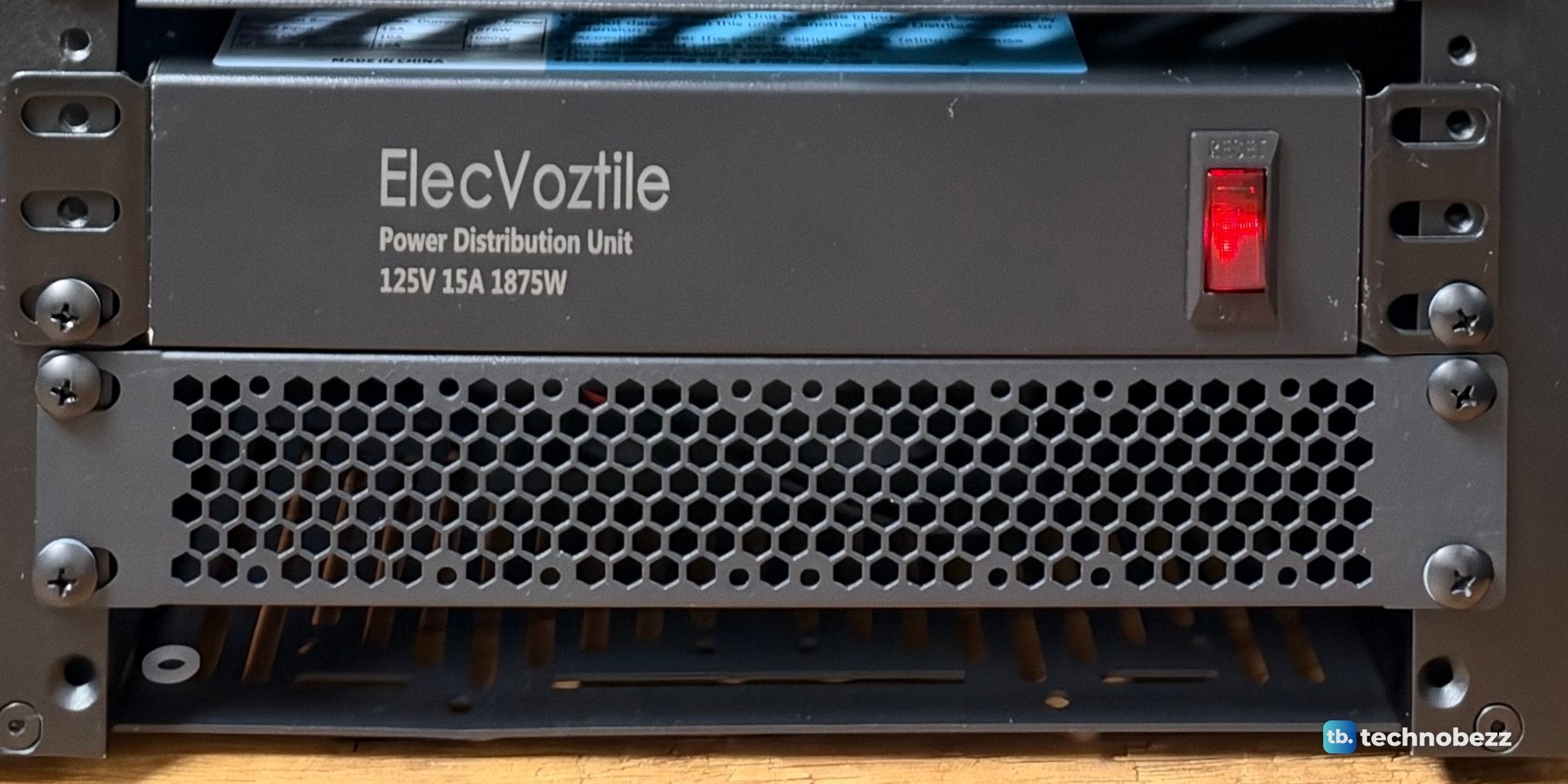 The ElecVoztile power distribution unit with its red front switch, mounted above a vented panel at the bottom of the rack