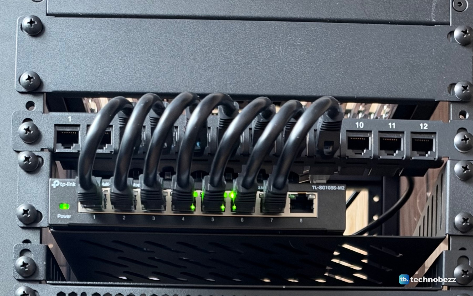 Short black patch cables looping from the 12-port patch panel down into the TP-Link TL-SG108S-M2 switch