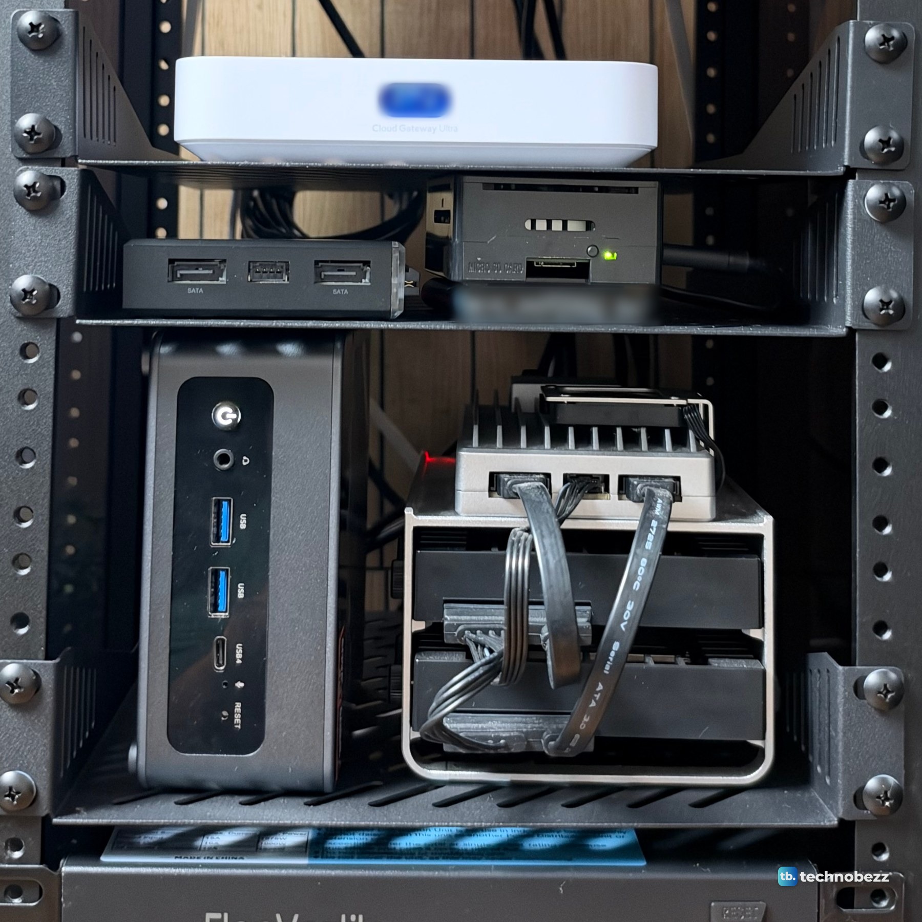 The UniFi gateway on one shelf, the ZimaBlade and Raspberry Pi 5 on the next, and the ACEMAGIC F5A beside the ZimaBoard 2 on the shelf below