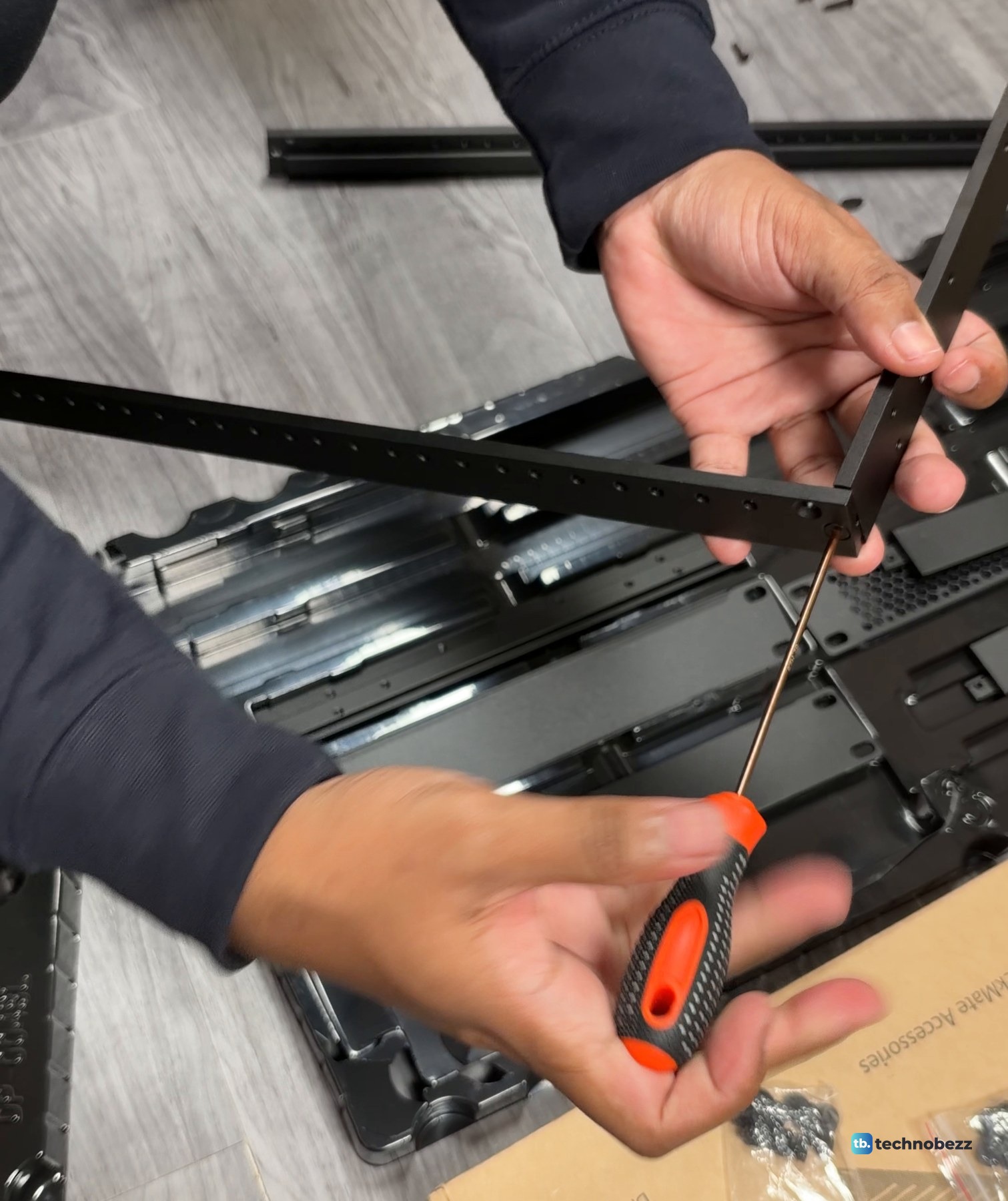 A hex driver tightening the corner screw that closes a DeskPi RackMate T2 side frame
