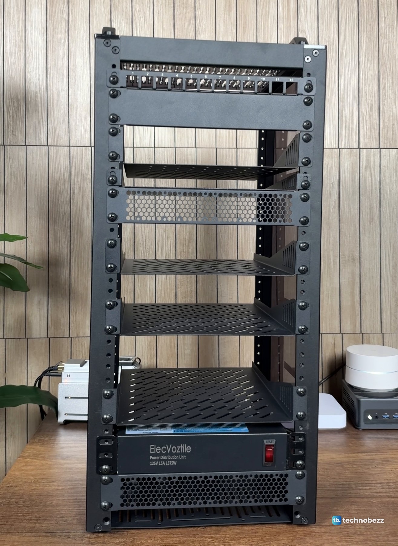 The assembled DeskPi RackMate T2 standing empty on a wooden desk with shelves, panels and the power strip fitted
