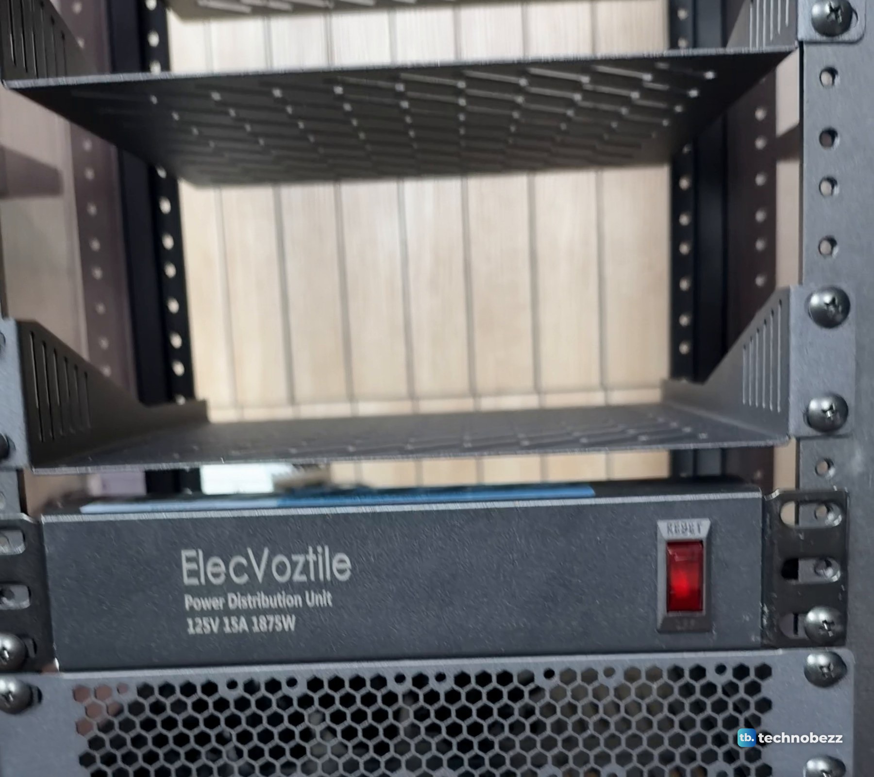 The ElecVoztile power strip mounted low on the front rails of a DeskPi RackMate T2 under the vented shelves