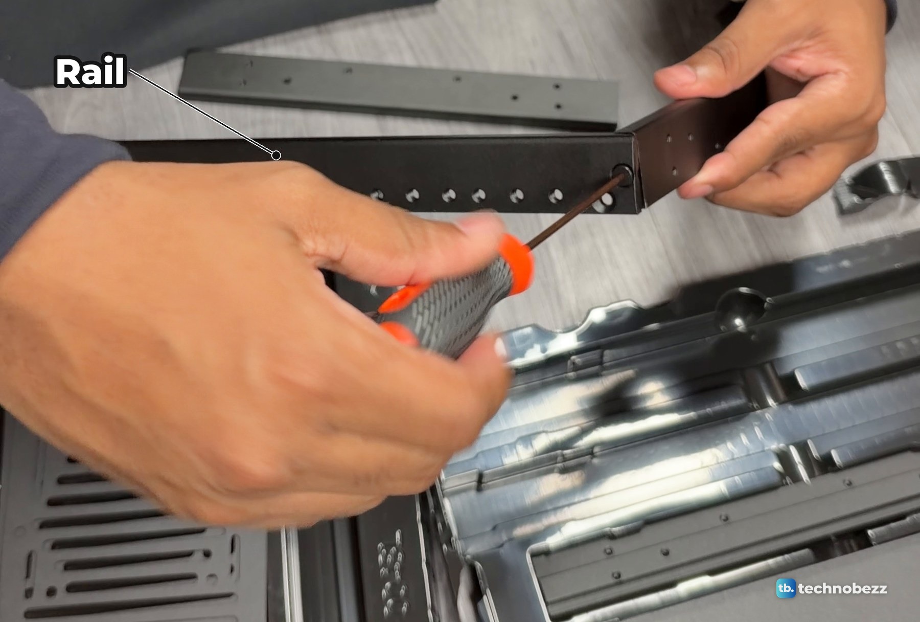 Hands driving a screw through the corner where a DeskPi RackMate T2 rail meets a crossbar