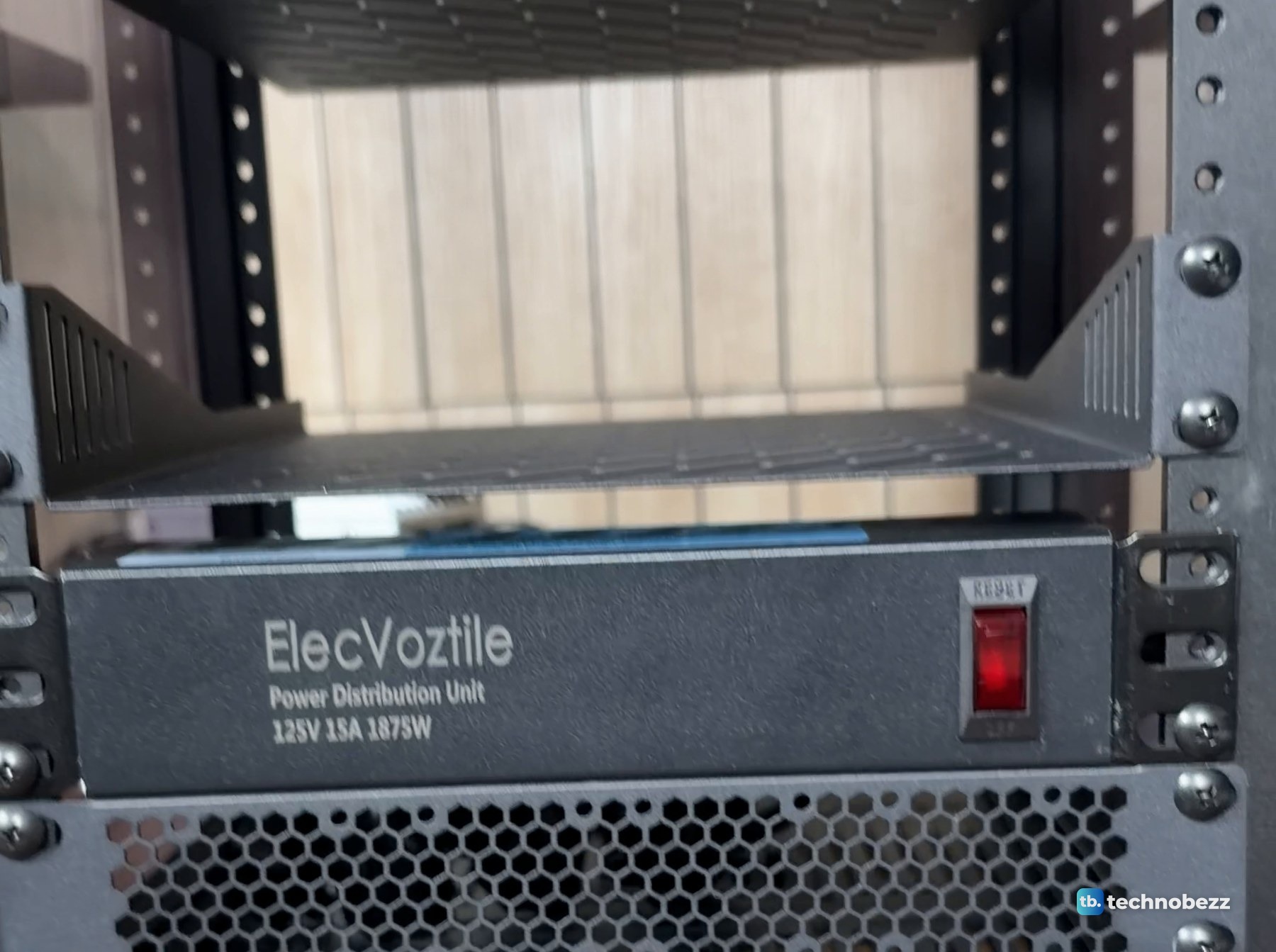 Front of the ElecVoztile 10-inch power distribution unit mounted low in the empty rack, with its red rocker switch and the 125V 15A 1875W rating printed on it