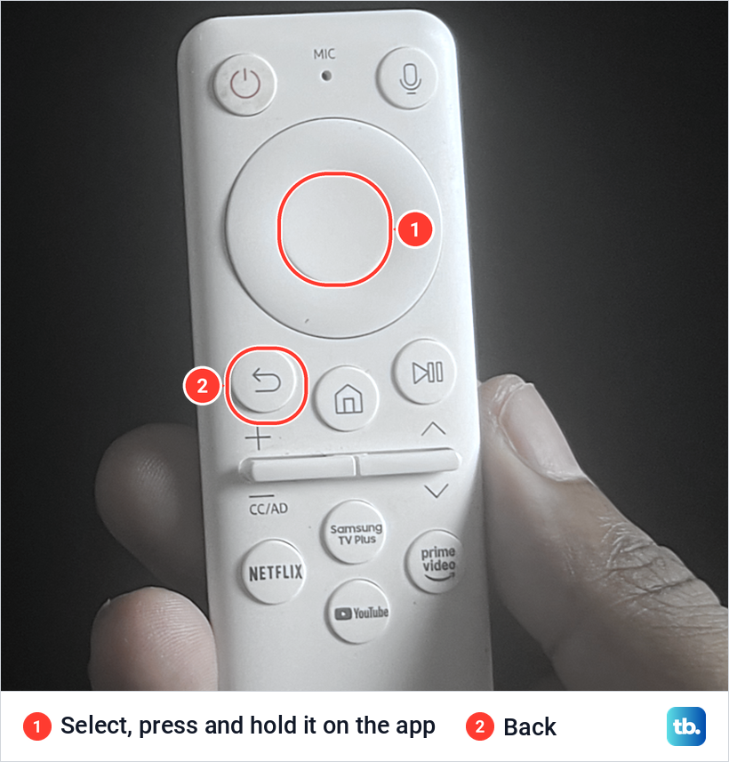 Close-up of a white Samsung remote in a hand with the centre Select button and the Back button marked.