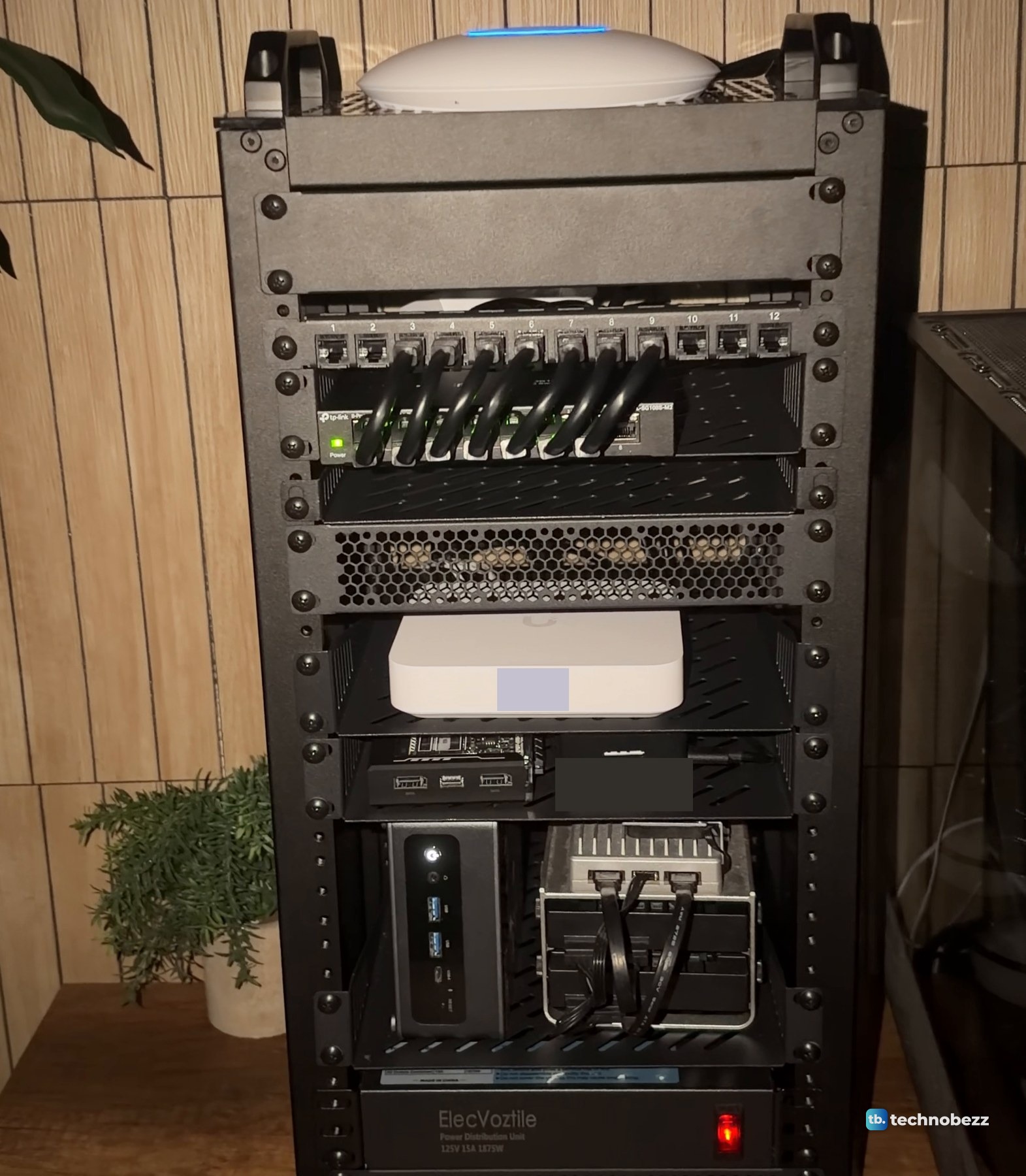 A 10-inch home lab rack in a dim room with green switch lights under a row of short jumpers