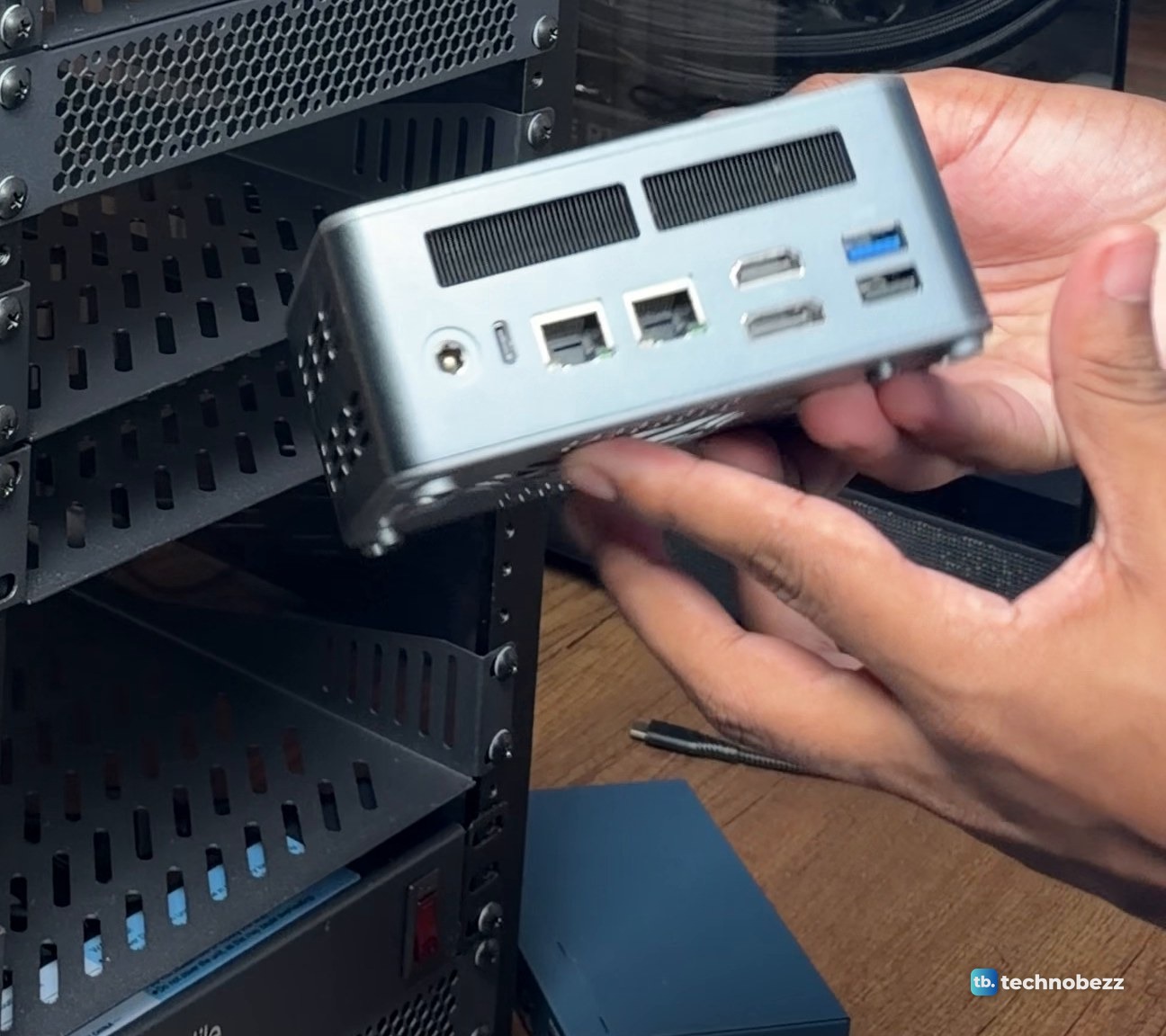 Rear of an ACEMAGIC F5A mini PC held in two hands showing two Ethernet jacks and other ports