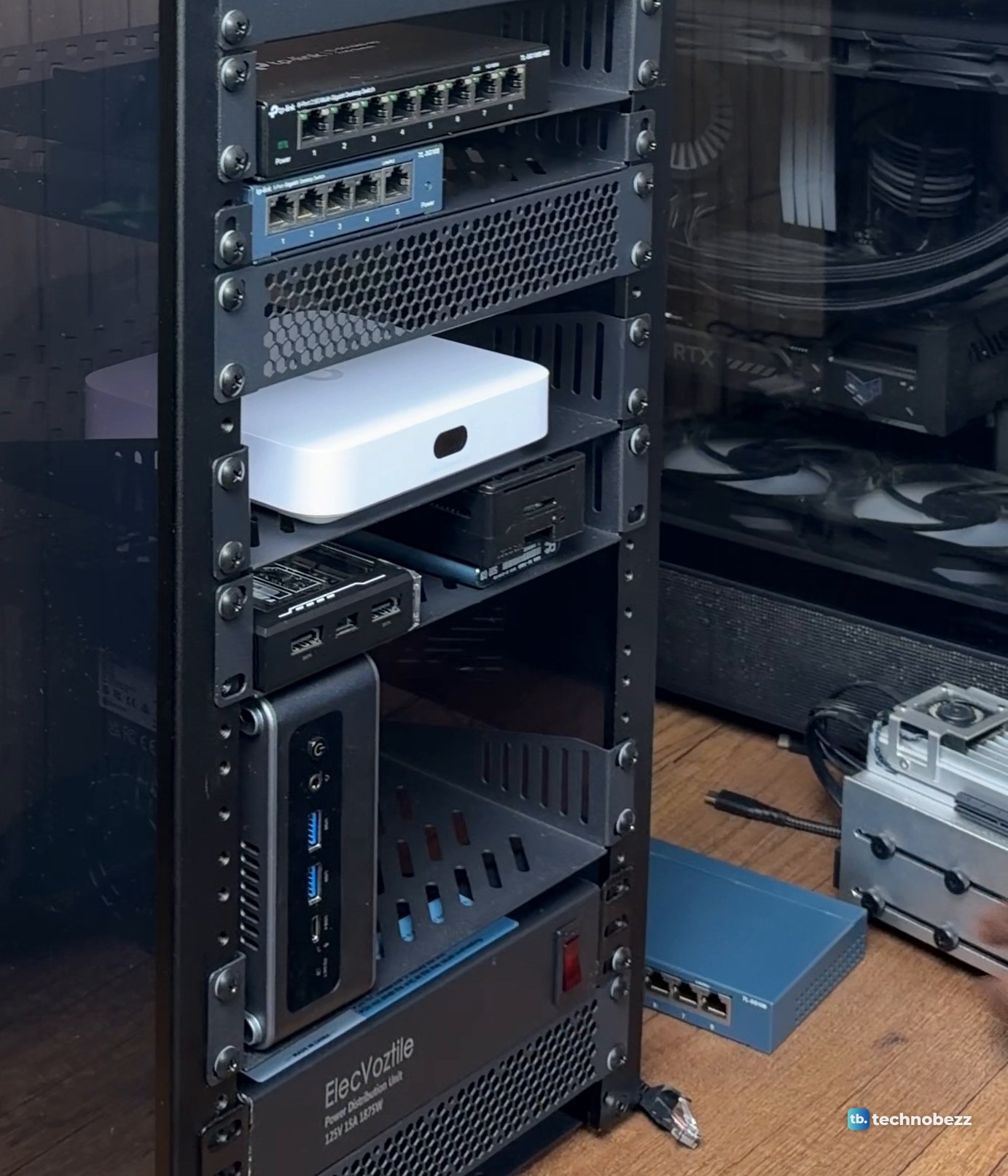 ACEMAGIC F5A mini PC standing upright on a rack shelf with its front ports facing out