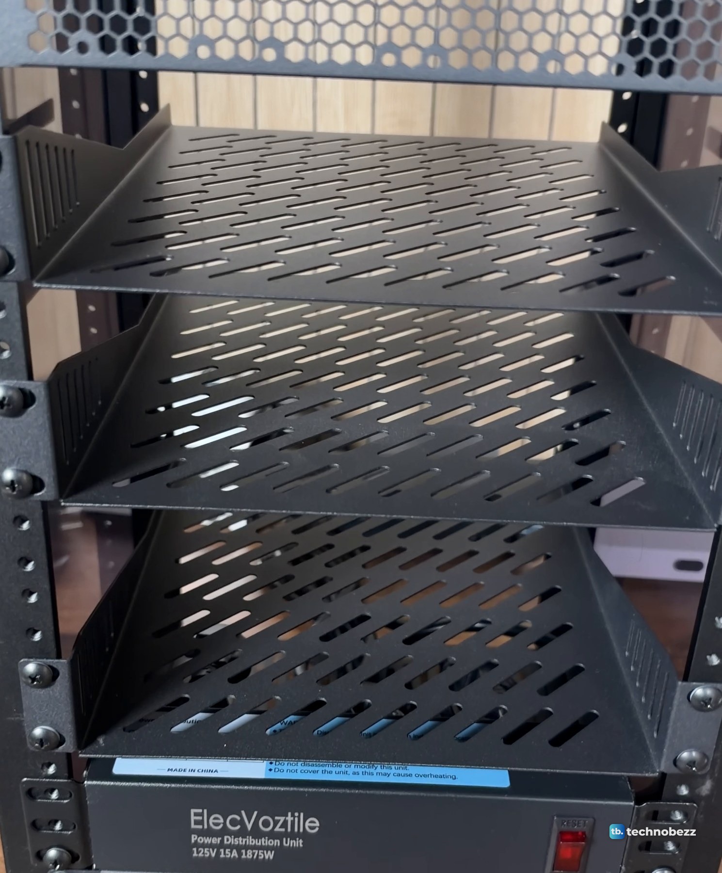 Empty black 1U vented shelves screwed into a DeskPi RackMate T2 above the power strip
