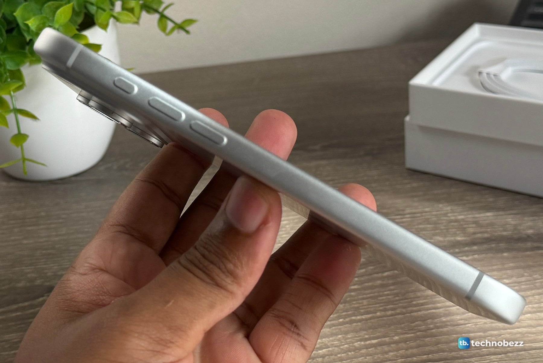 Left side of a silver iPhone 18 Pro Max held in a hand, showing the Action button, two volume buttons and a smooth rail below them