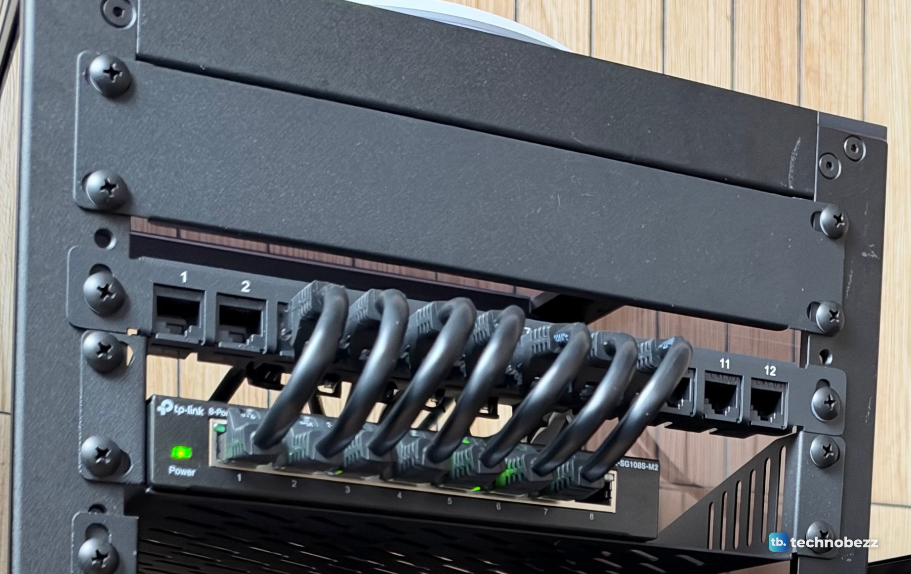 A thin 0.5U patch panel with short black jumpers mounted under a full-height 1U blank panel