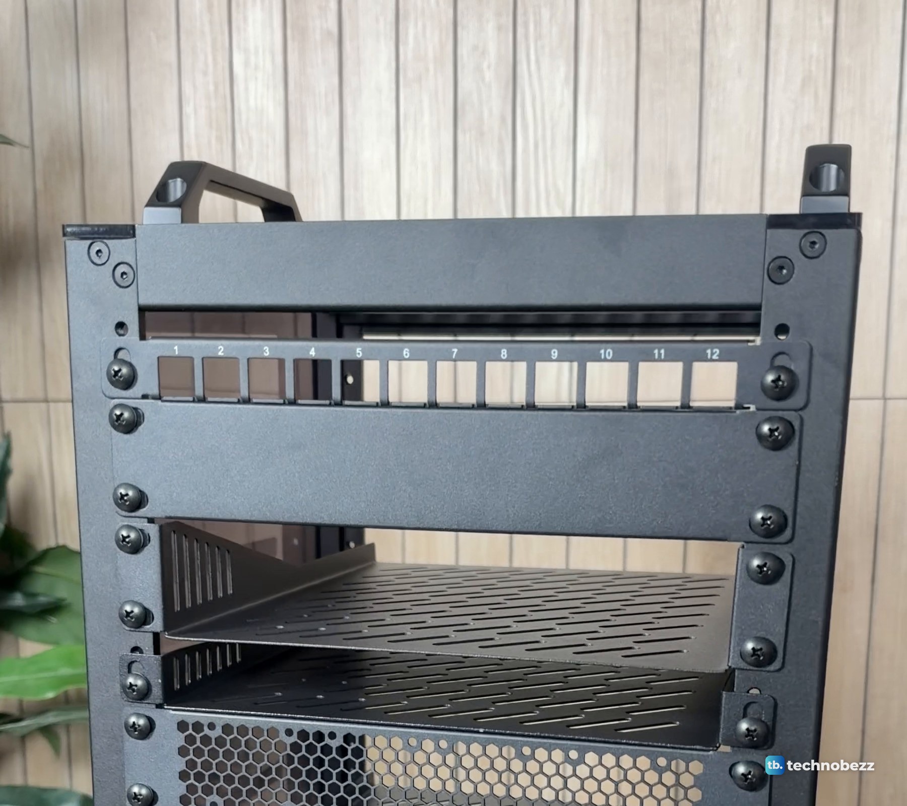 Empty DeskPi RackMate T2 with a 12-port patch panel screwed in near the top and vented shelves below