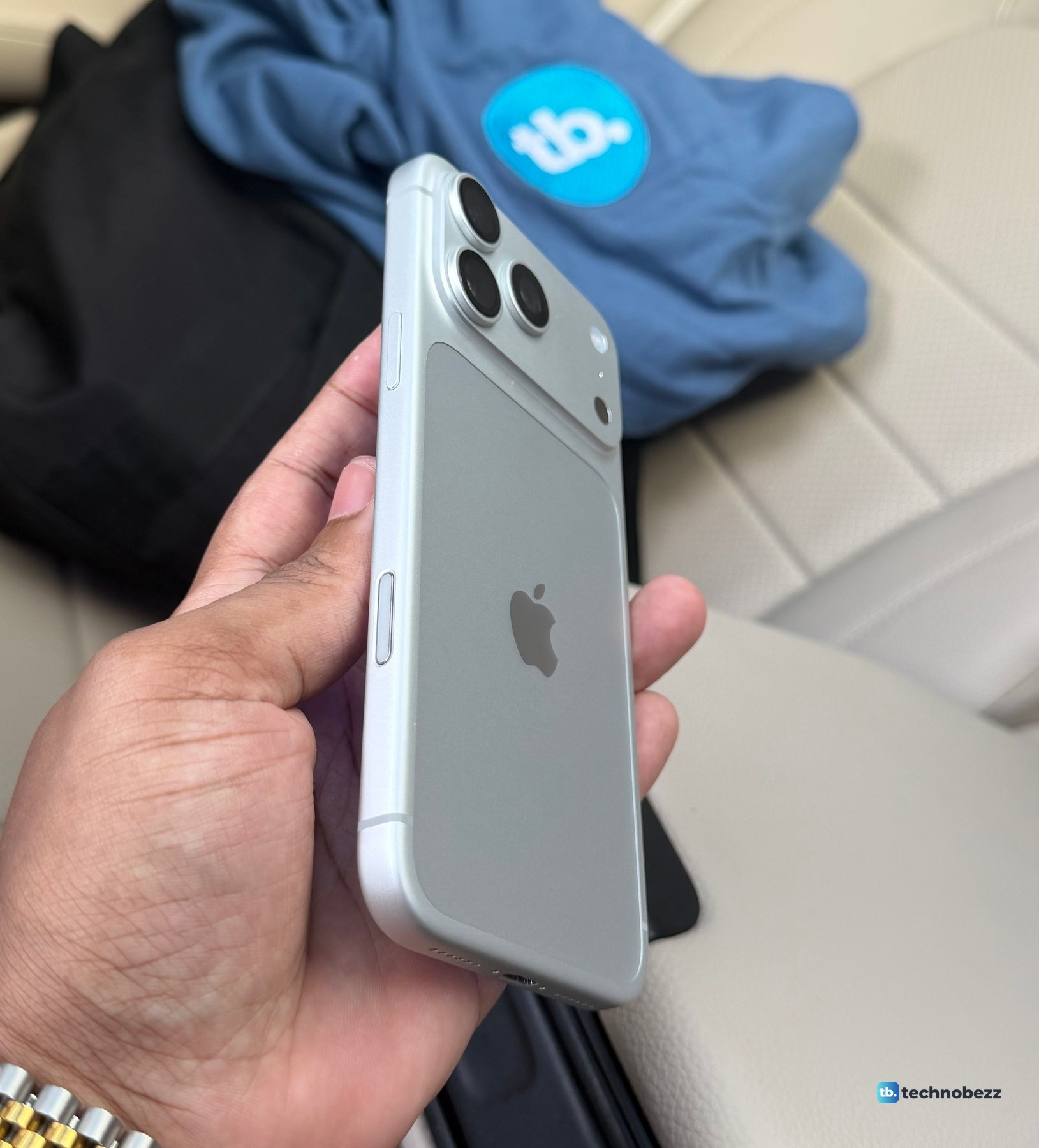 The right side of a silver iPhone 18 Pro Max held in a hand, with the side button near the cameras and the Camera Control lower down the same edge