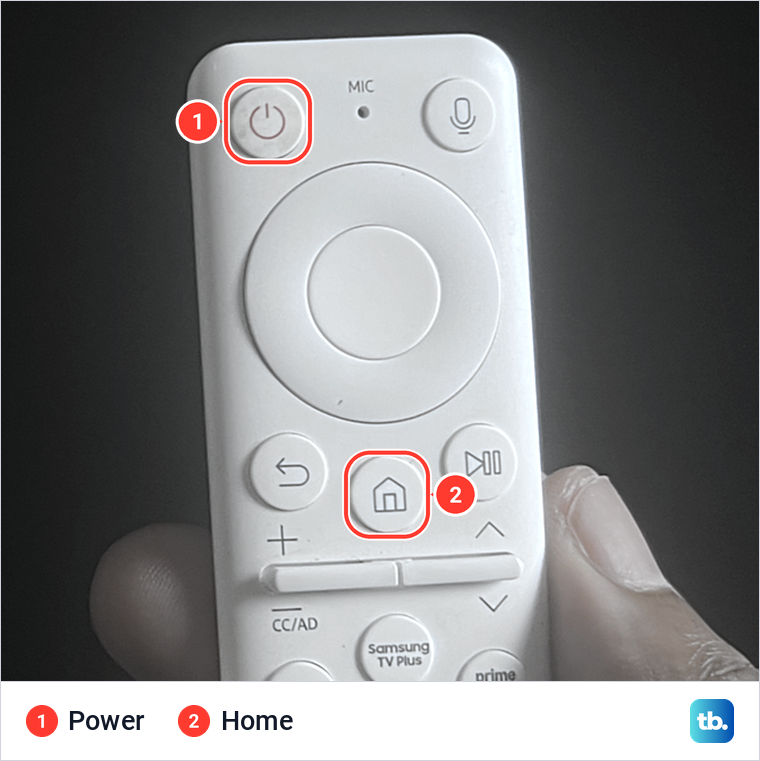 A hand holding a white Samsung remote with the Power and Home buttons marked.