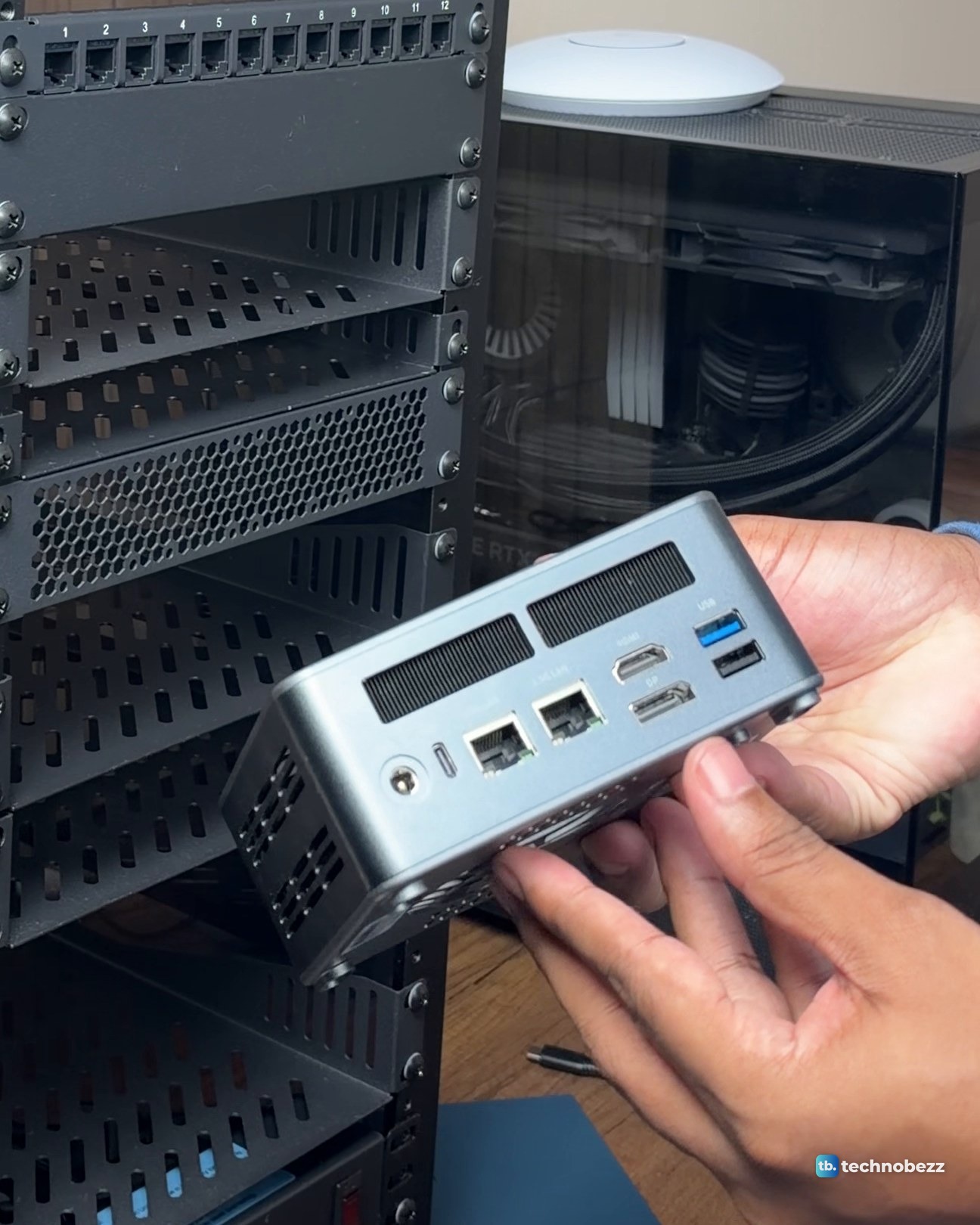 Two hands holding the grey ACEMAGIC F5A mini PC, showing two Ethernet ports, HDMI and USB ports on the back