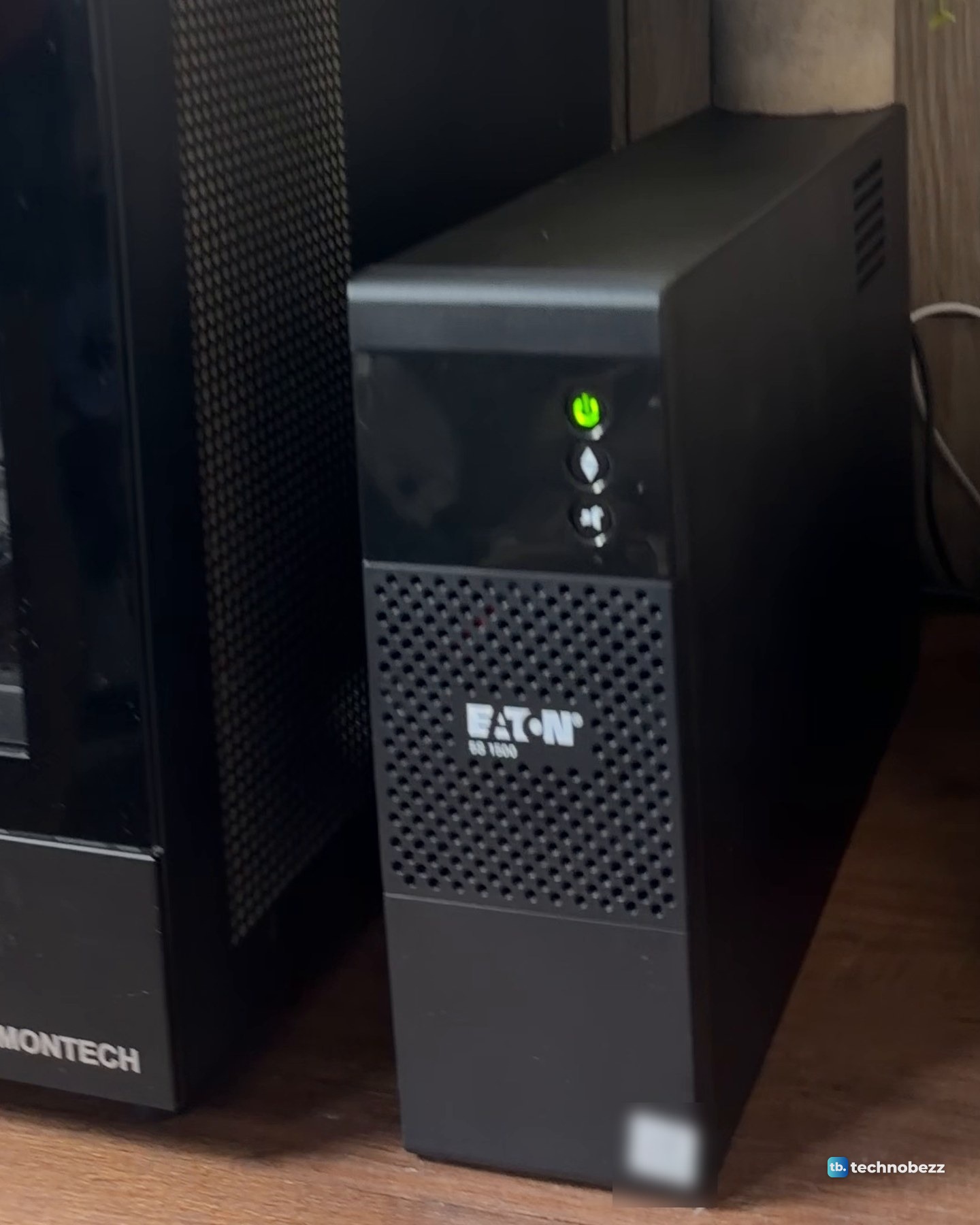 A black Eaton 5S 1500 UPS standing upright on a wood desk next to the black main server case