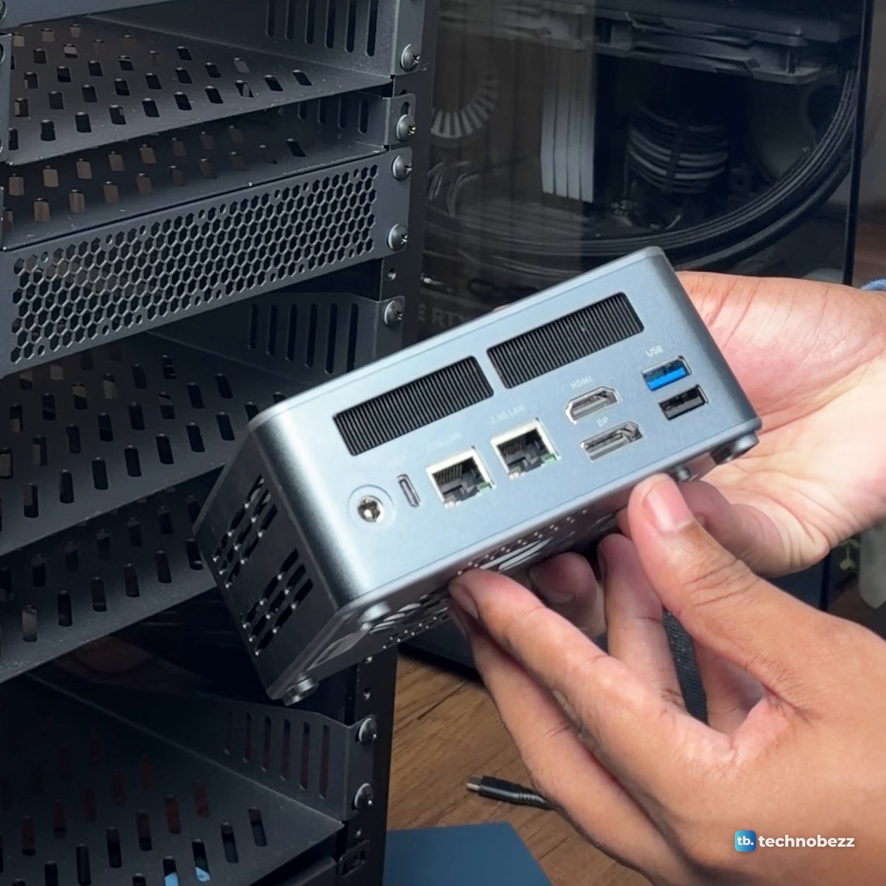 Hands holding the grey ACEMAGIC F5A mini PC, showing two Ethernet ports, HDMI and USB ports on the back