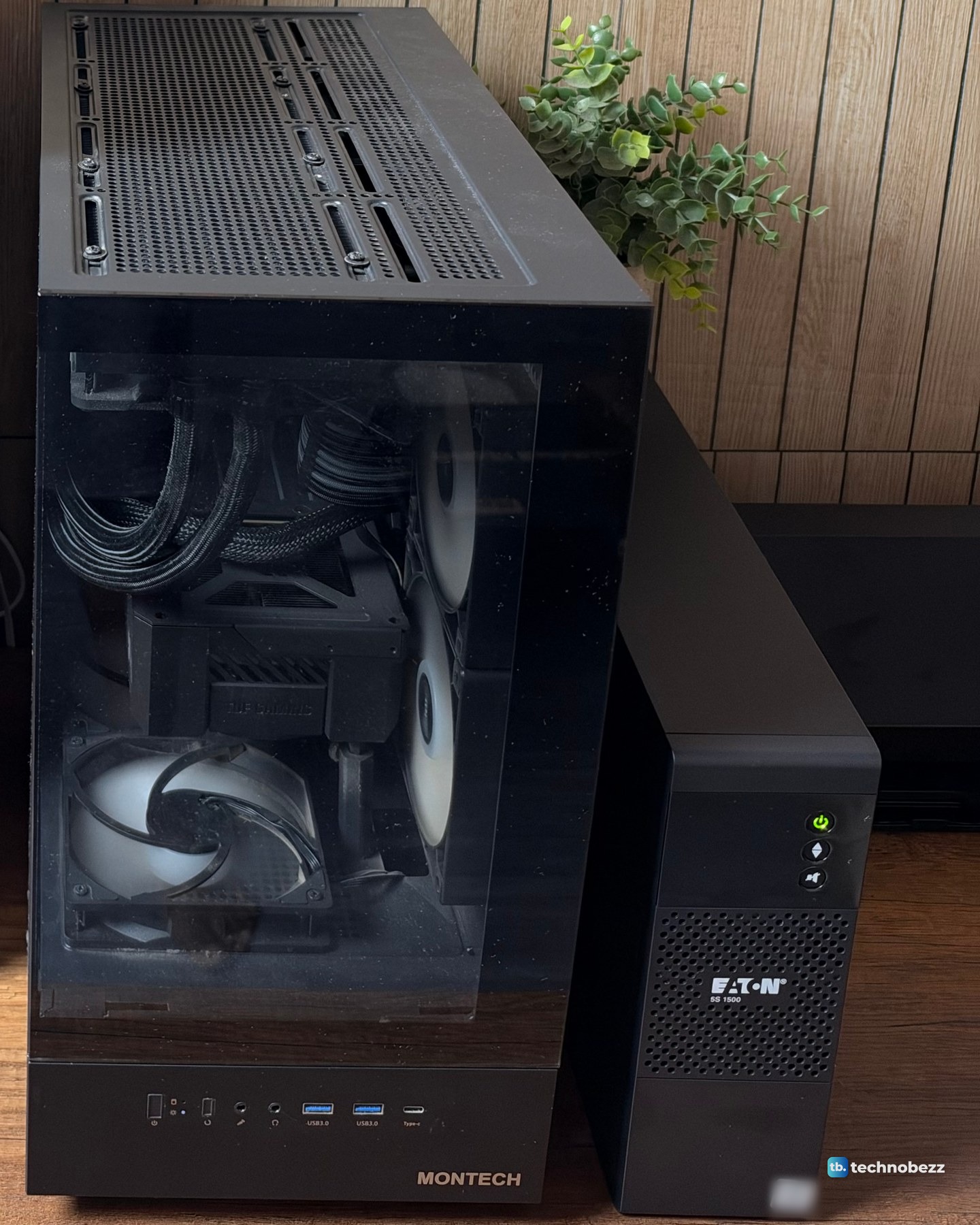 The black MONTECH tower PC with a glass side and the black Eaton 5S 1500 UPS standing beside it