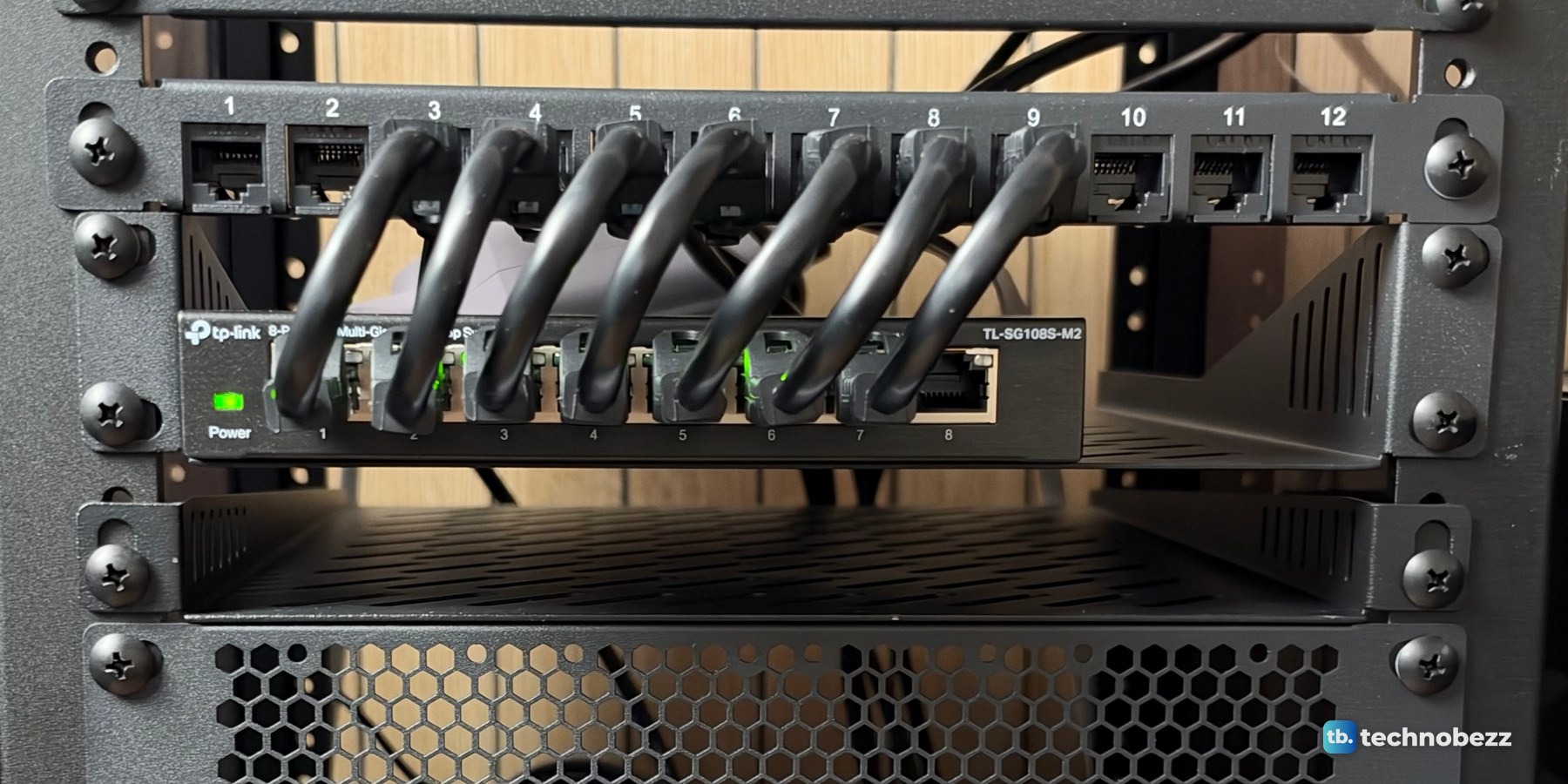 Seven short black jumpers looping from the patch panel down into the ports of the TP-Link TL-SG108S-M2 switch