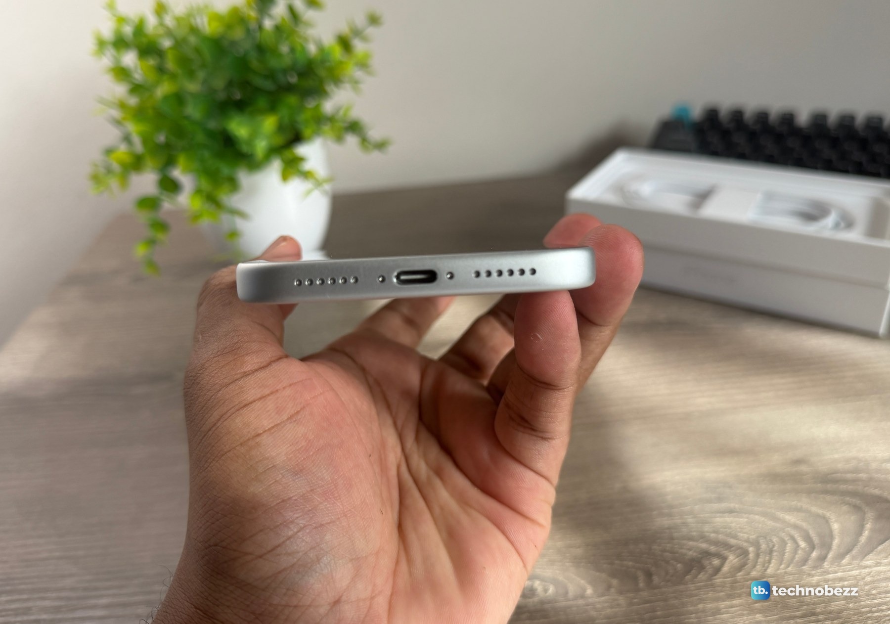 The bottom edge of the iPhone 18 Pro Max held in a hand, showing the USB-C port and a row of holes on each side