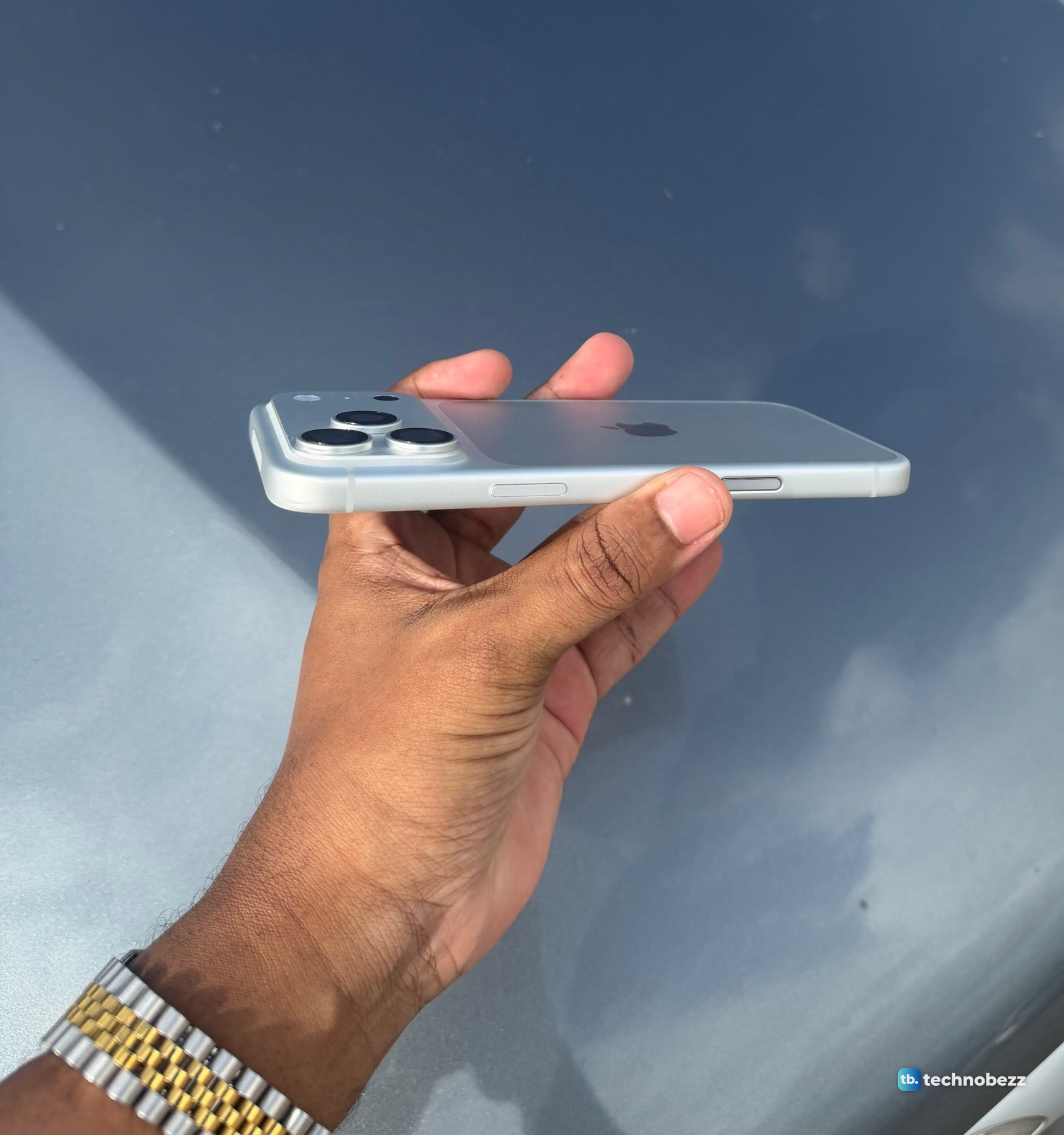 The iPhone 18 Pro Max held flat and seen from the side, with the camera bar and lenses rising above the back