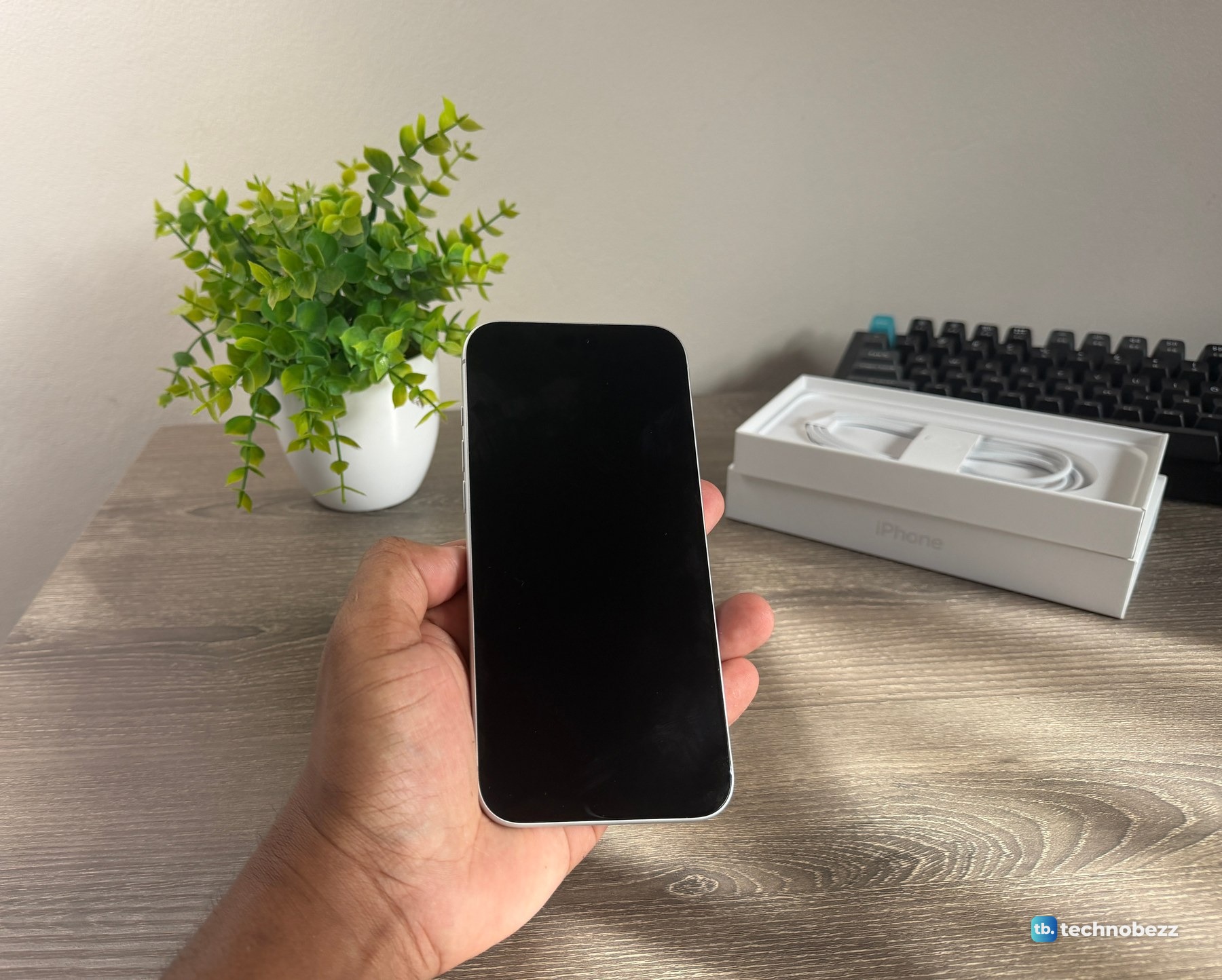 The front of the iPhone 18 Pro Max with the screen off, lying in an open palm above a desk