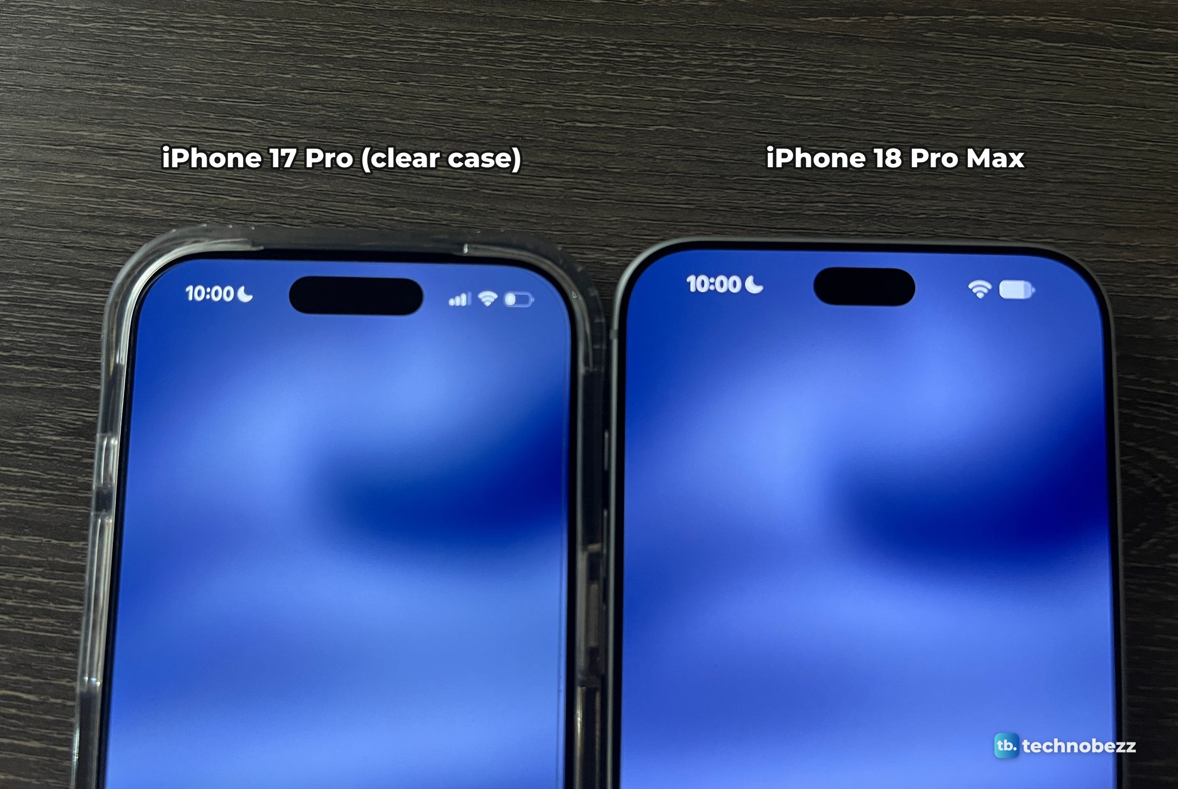 The top halves of an iPhone 17 Pro in a clear case and an iPhone 18 Pro Max lying side by side on a dark desk, both screens on