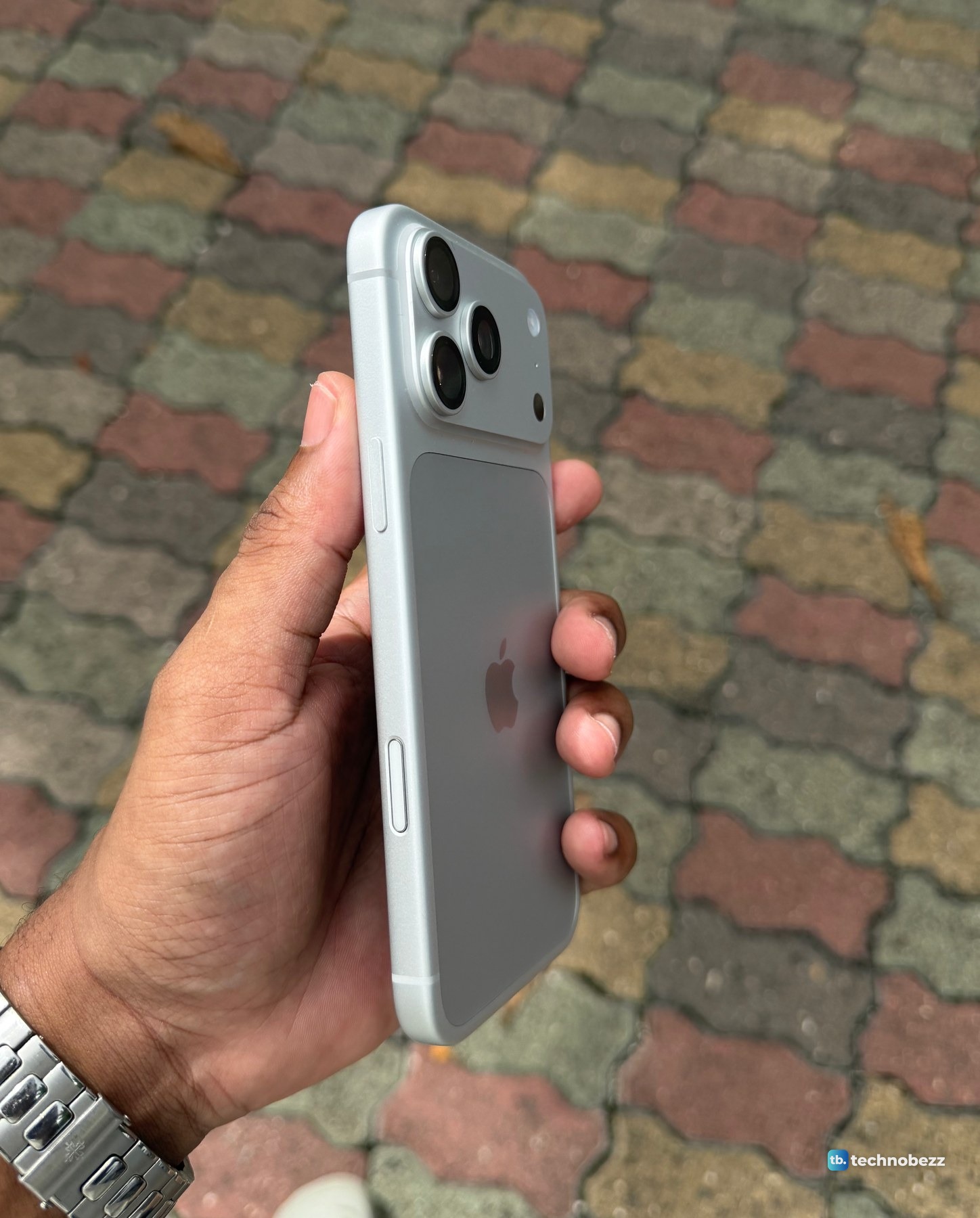 A three-quarter view of the iPhone 18 Pro Max in one hand, showing the side rail, two buttons and the raised camera bar