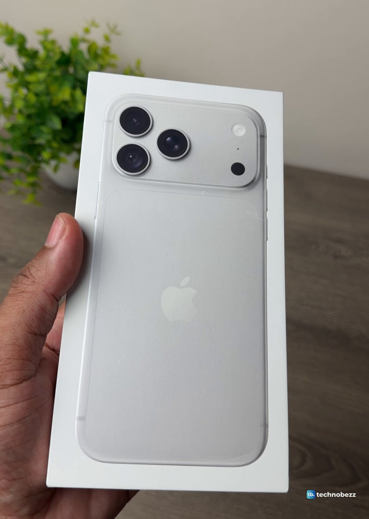 Hand holding the closed white iPhone 18 Pro Max box, front side up