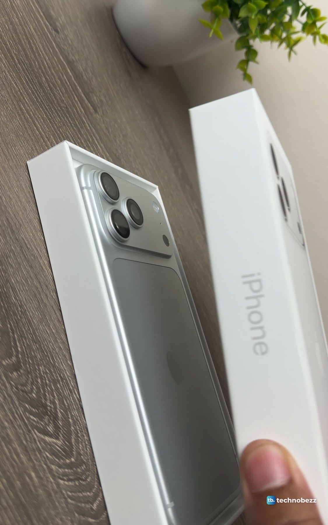 Box lid being lifted away to show the silver iPhone 18 Pro Max lying face down in its tray