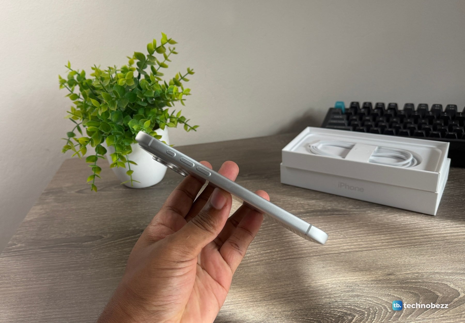 Side profile of the silver iPhone 18 Pro Max held flat in a hand, showing three buttons near the top of the edge